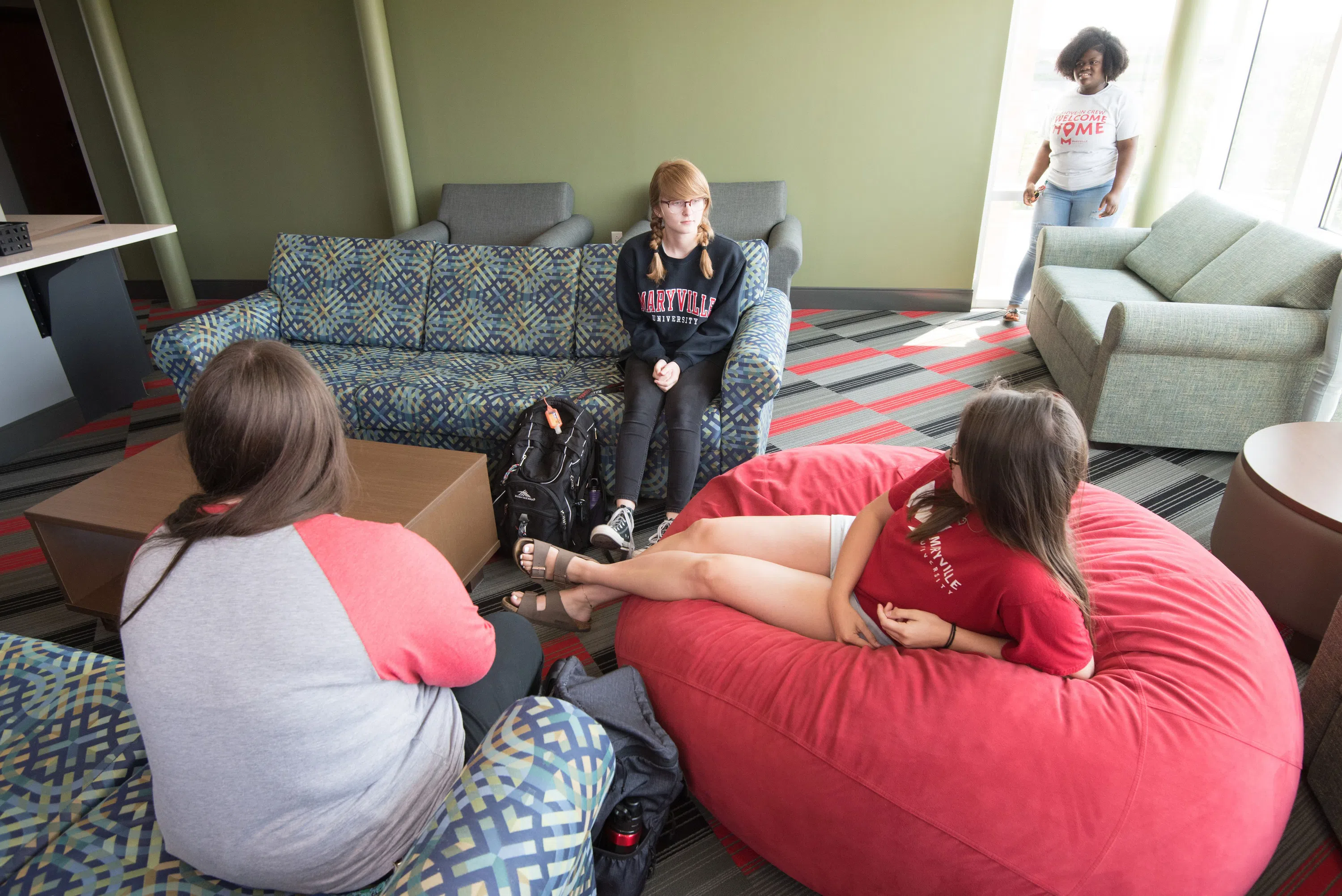 Students sit on couches and beanbag chairs in one of the lounges in Saints Hall.