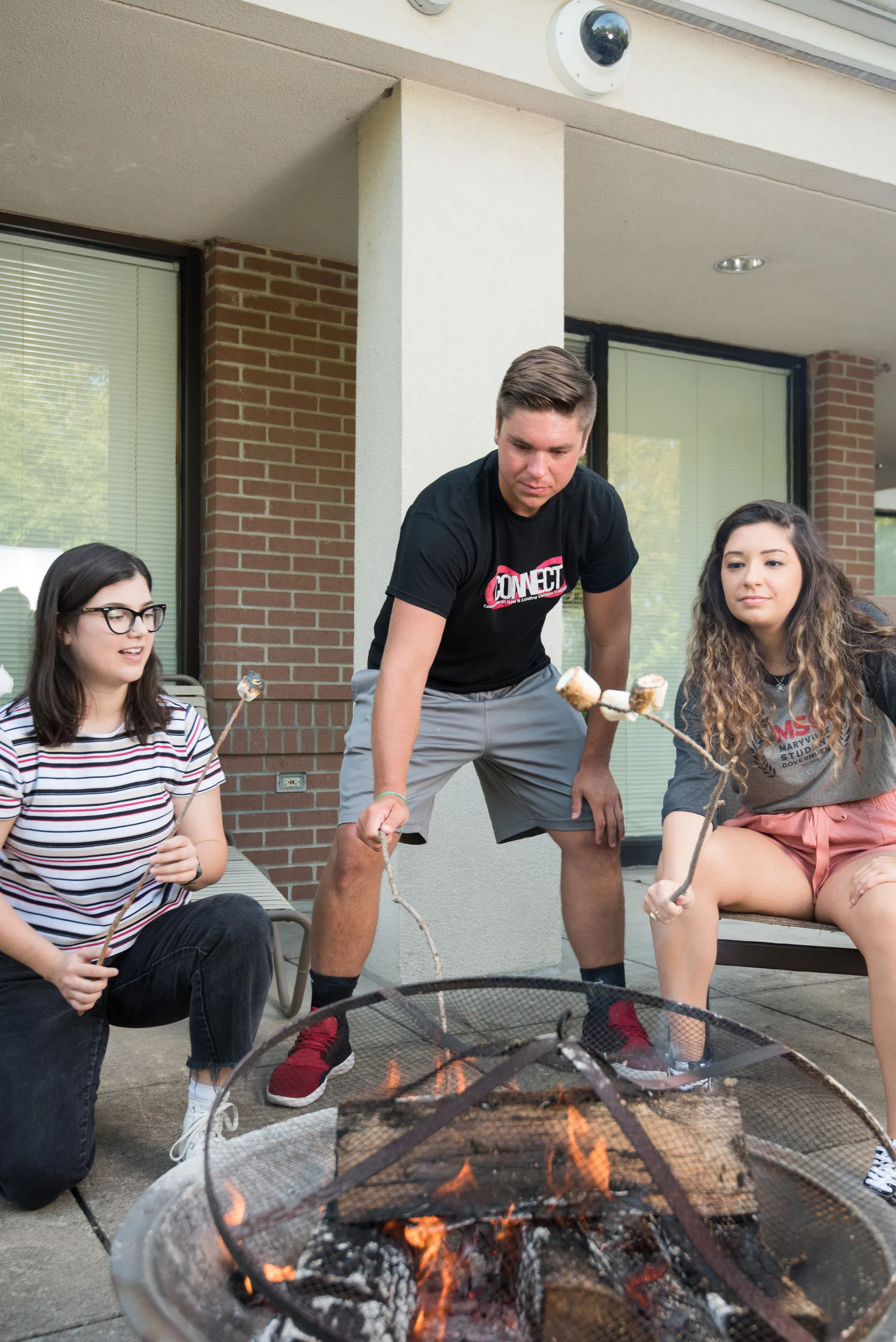 Students roast marshmallows at a firepit in the Potter Hall courtyard.