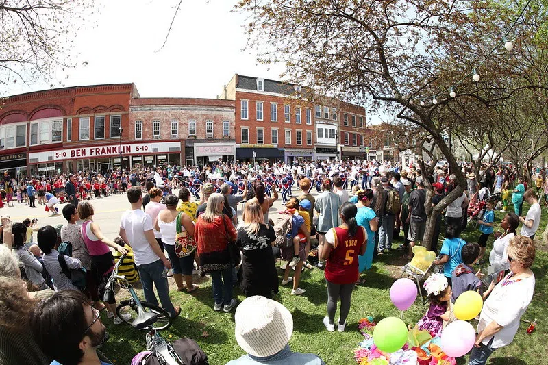 A crowd stands on either side of the street while the colorful and lively Big Parade makes its way through downtown Oberlin. 