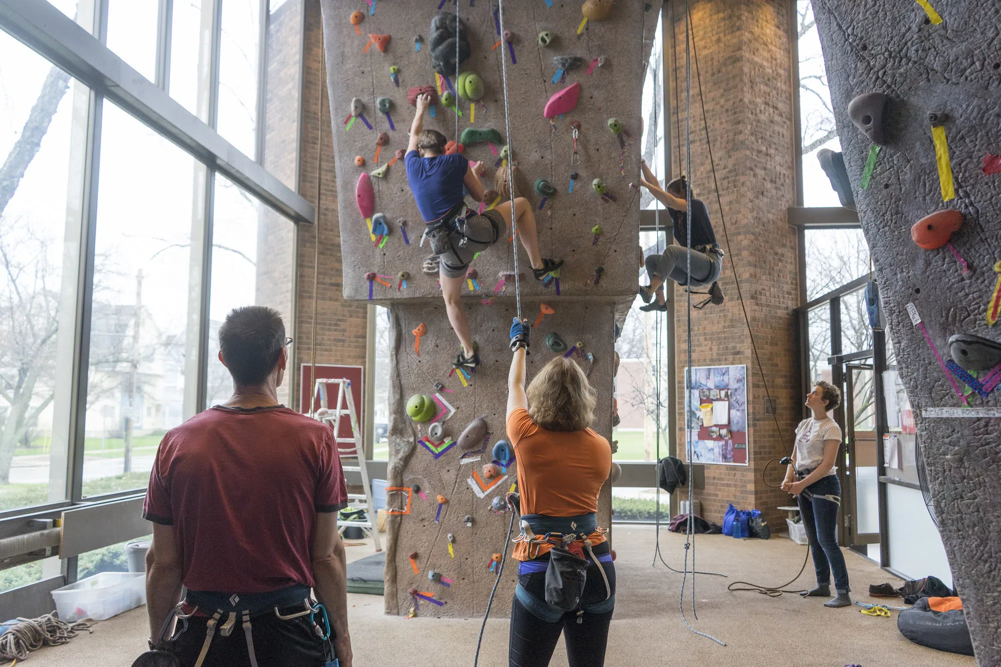 A few students climb on the colorful rock-climbing wall.