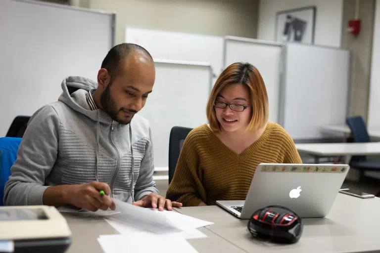 Two Students sit and work on a piece of writing