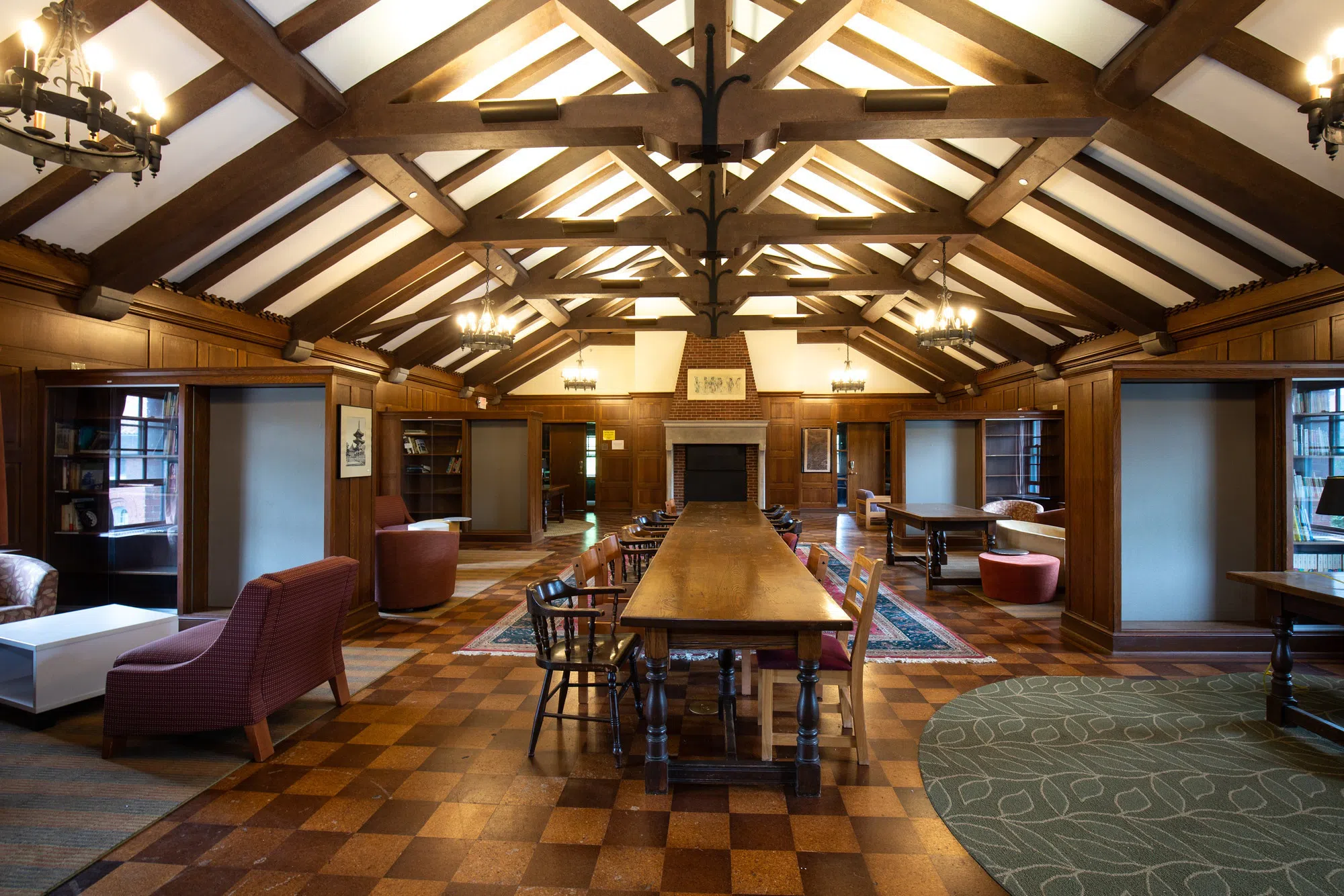A large A frame library is lit with warm lighting and dark wood furniture.