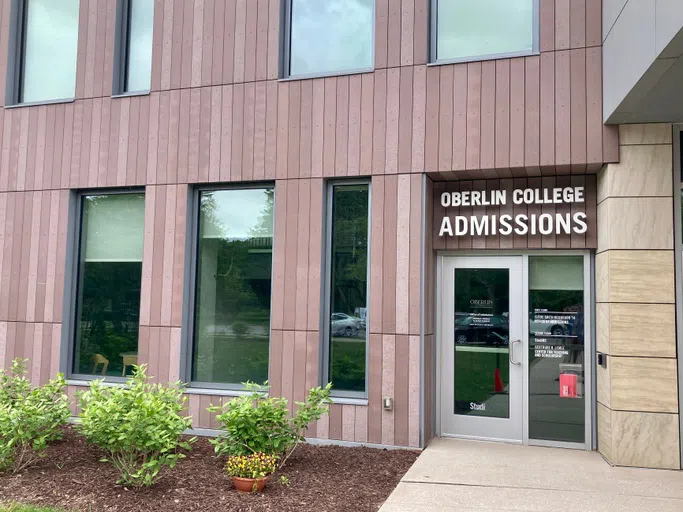 A brown building with windows features the sign 'Oberlin College Admissions'. 