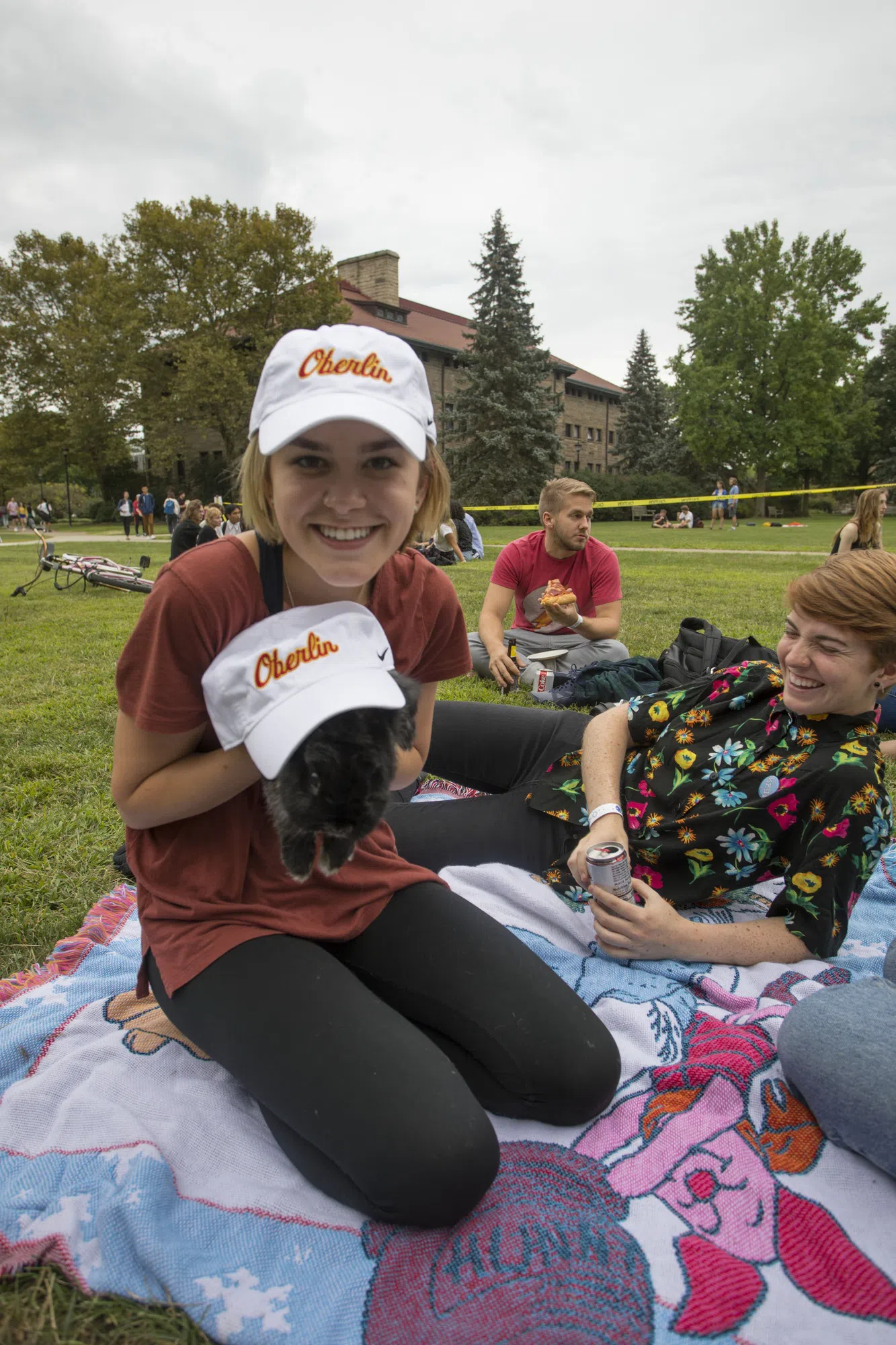 A smiling student shows her rabbit, wearing an Oberlin baseball cap.