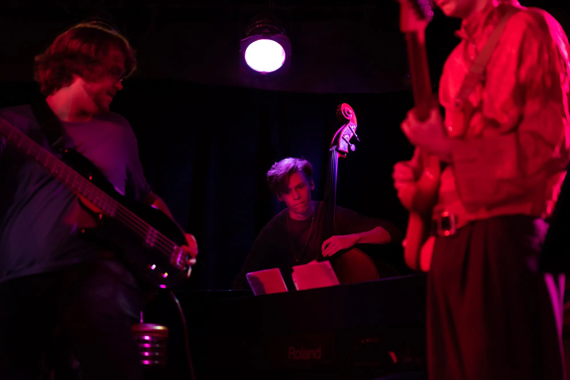 An upright bass player hits notes in the red lighting of Oberlin's nightclub venue, the Sco
