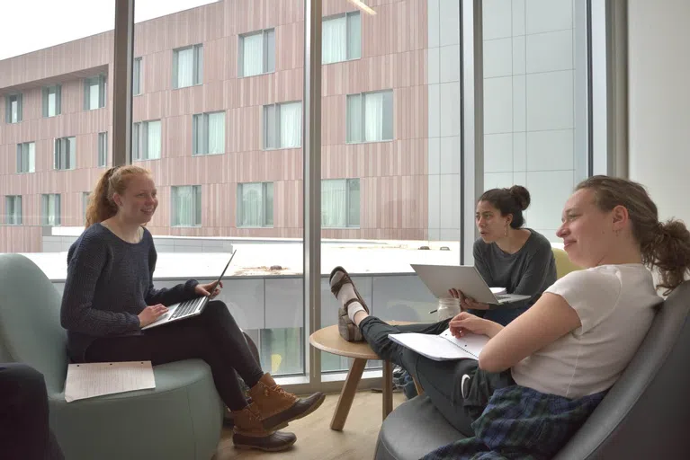 Three students sit in StudiOC and study. 