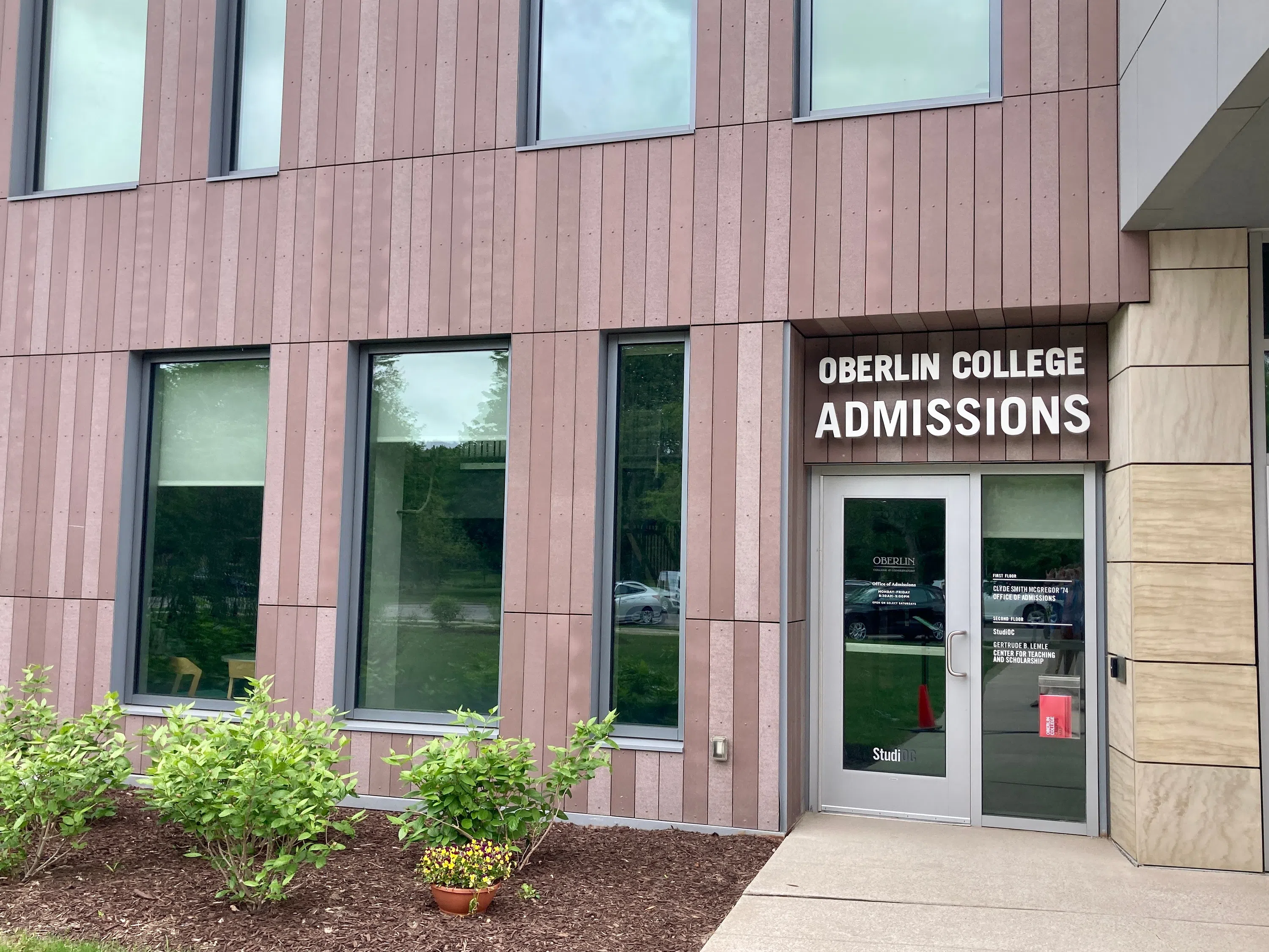 A brown building with windows features the sign 'Oberlin College Admissions'. 