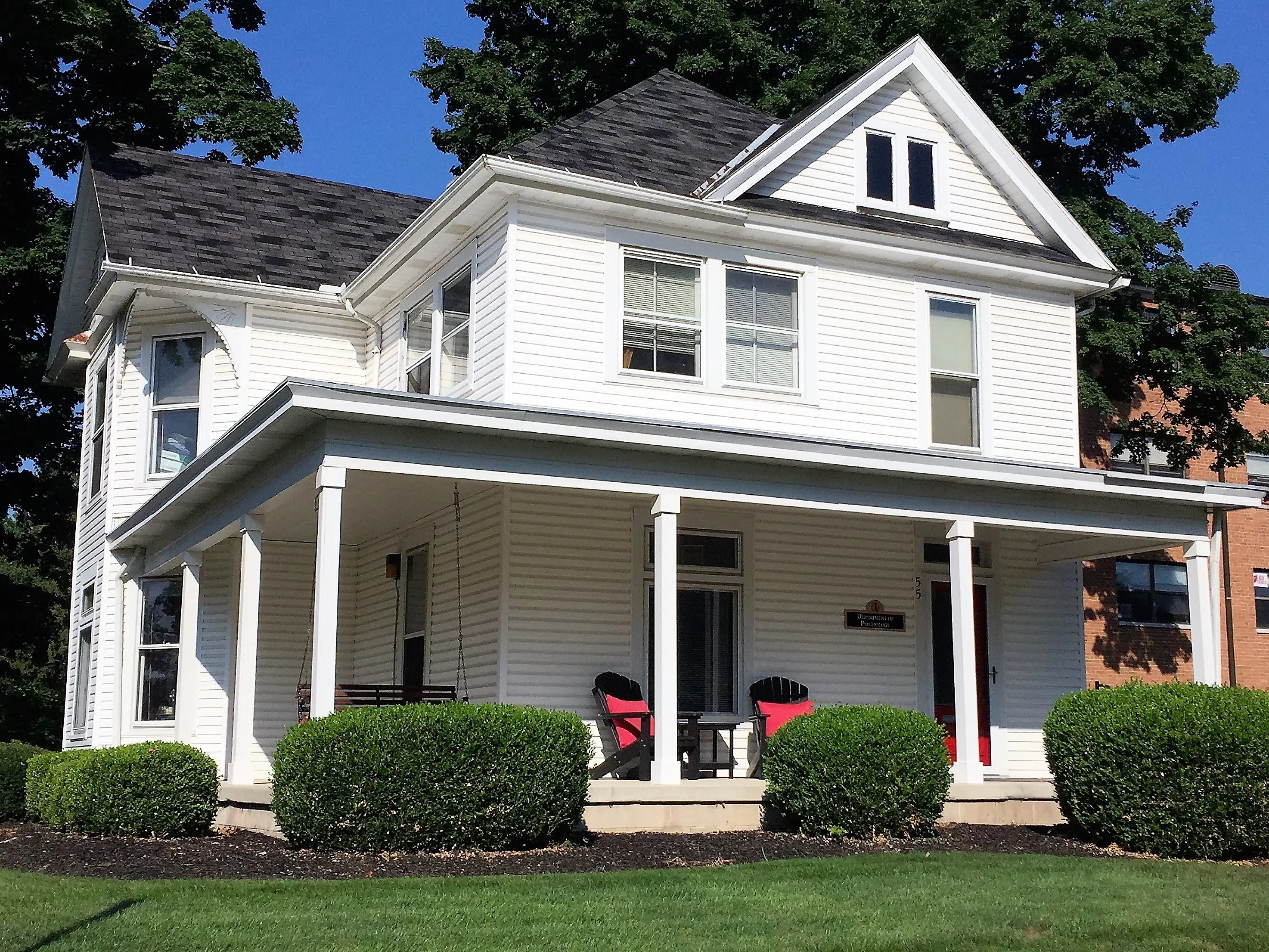 The Psychology House is a three story white house with an inviting and welcoming front porch.