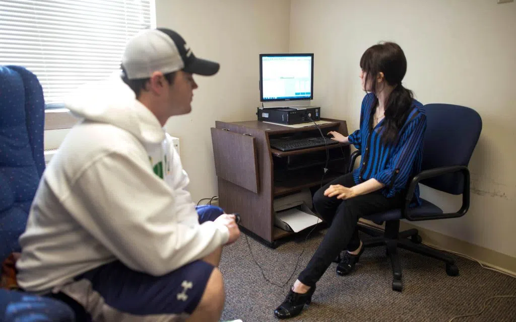 A student and advisor are sitting in a room together monitoring a computer screen.