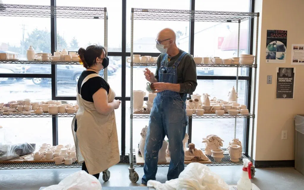 Two people speaking in a ceramics studio