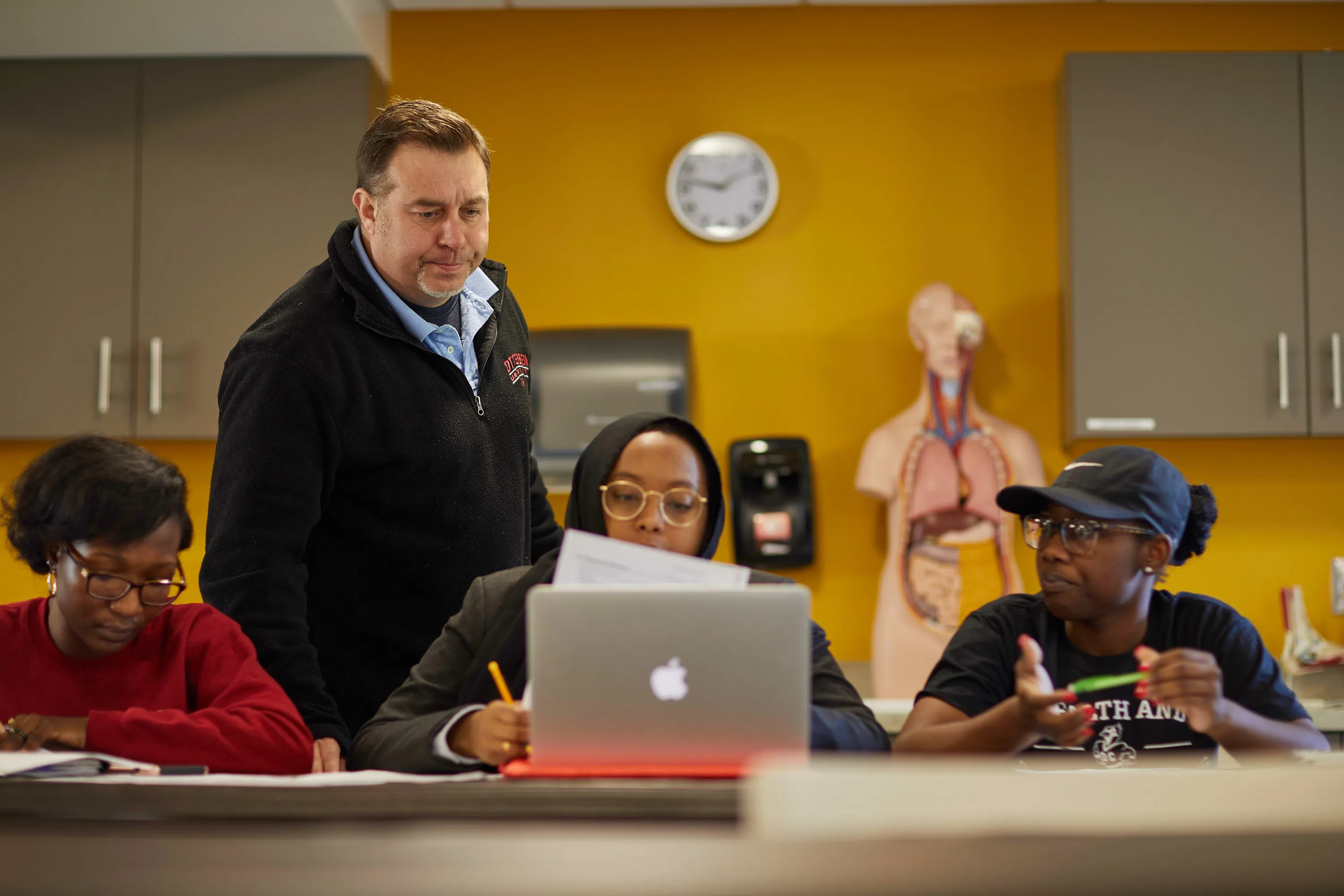 A teacher helping a group of 3 students.