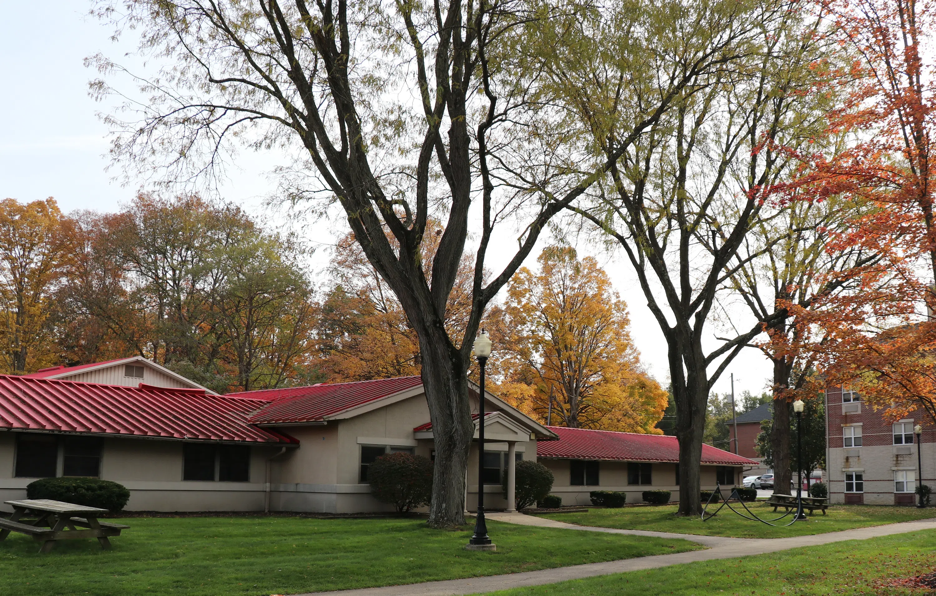 Main view of Scott Hall. A one-story building surrounded by green areas with trees and picnic tables.