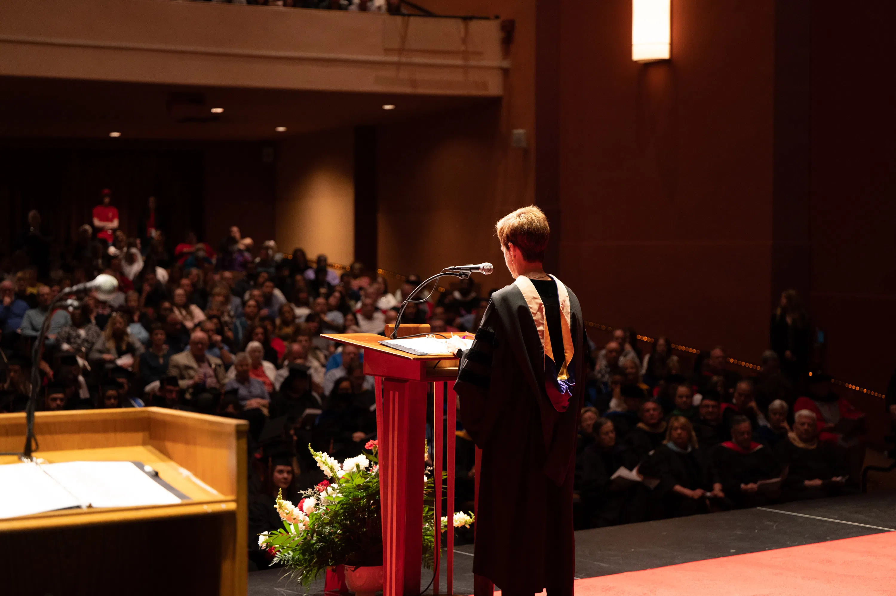 A person is giving a speech to a large audience at commencement.