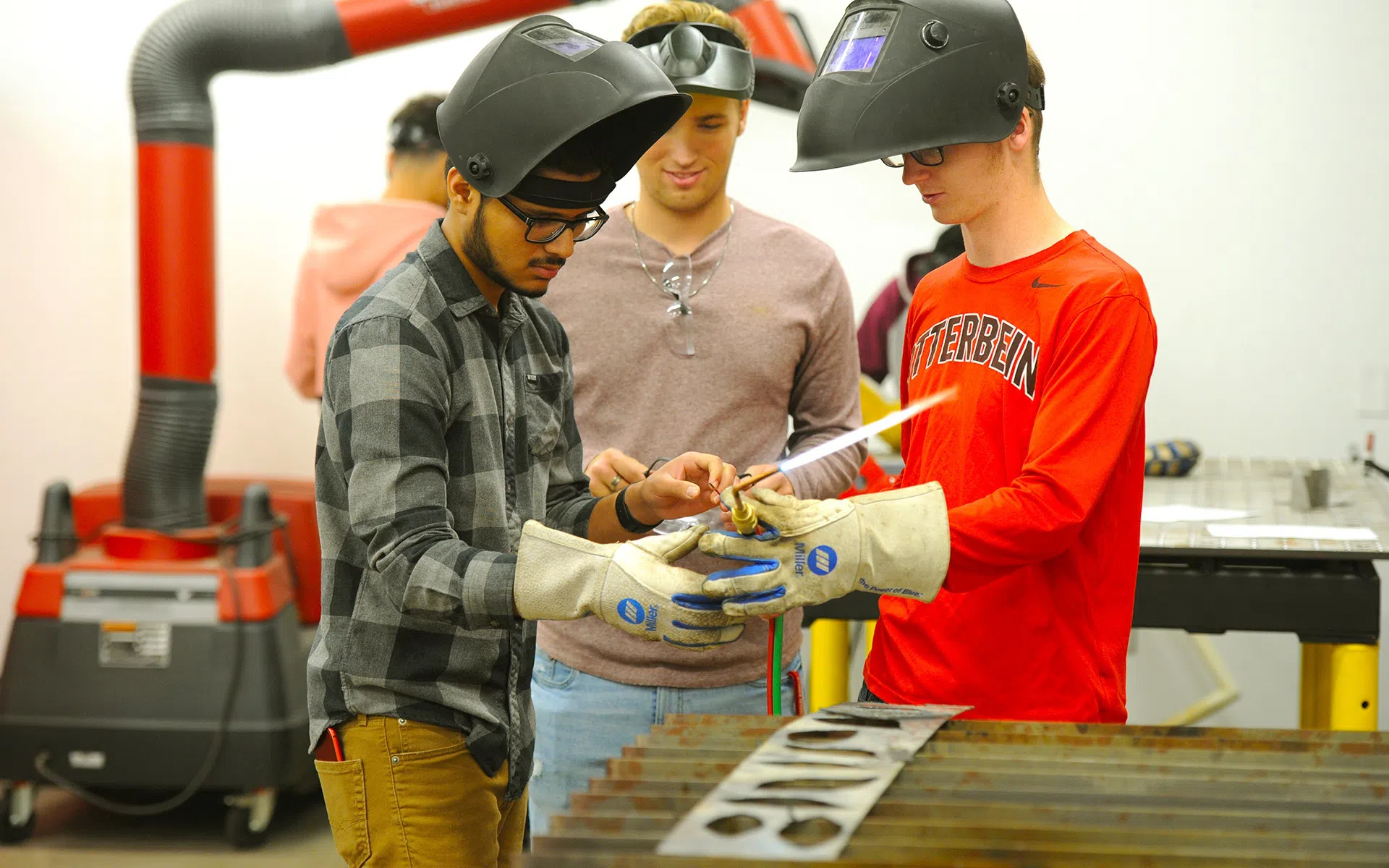 A group of students use a soldering torch for a project.