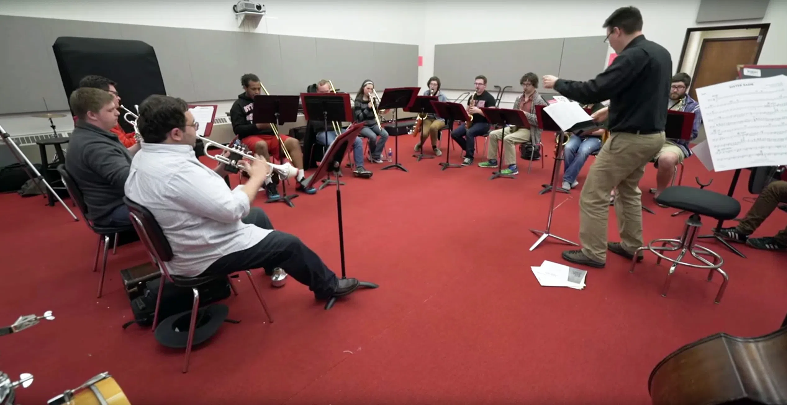 A group ensemble practicing together in a room with a red carpet and white walls.