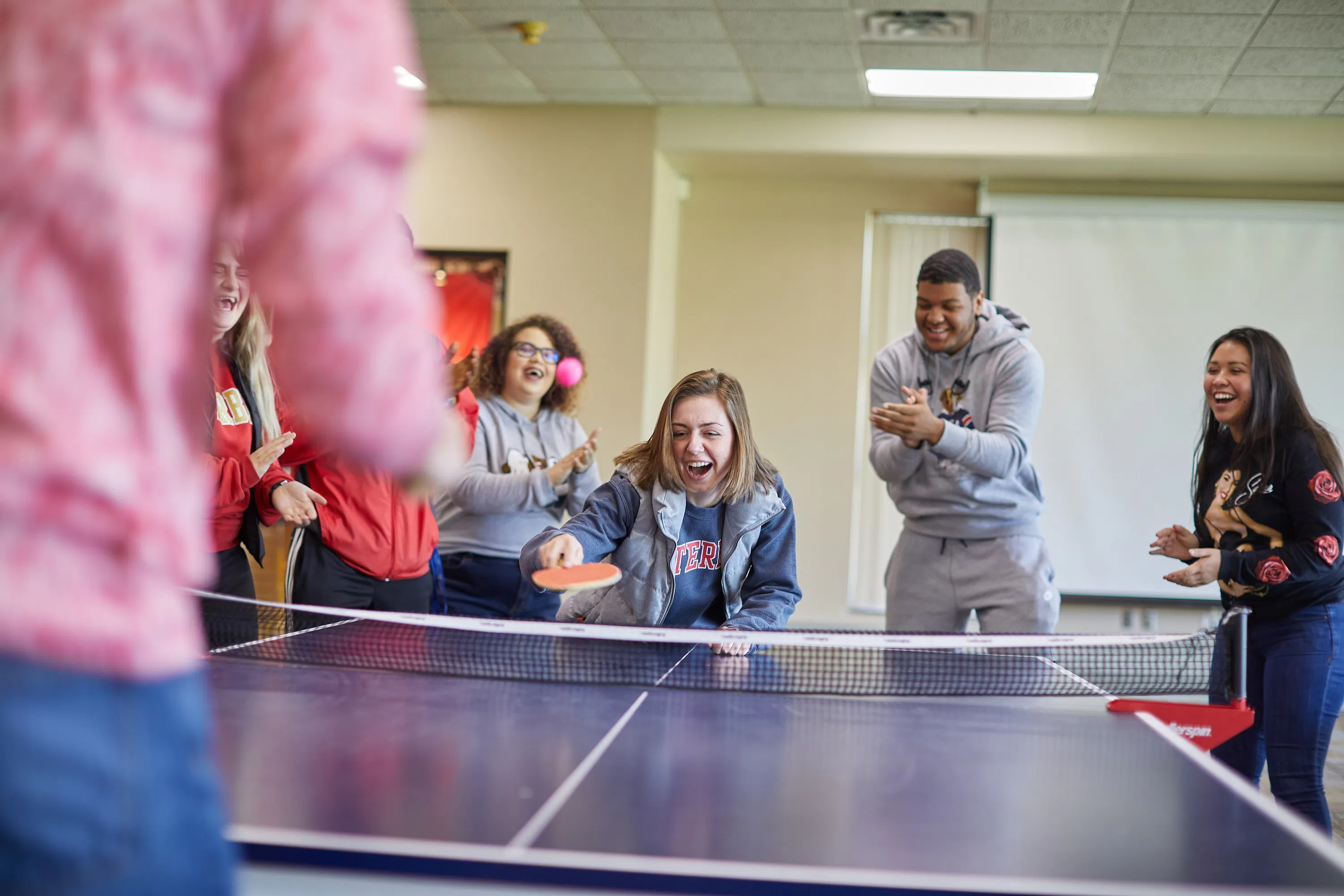 A diverse group of students play ping pong at the Campus Center