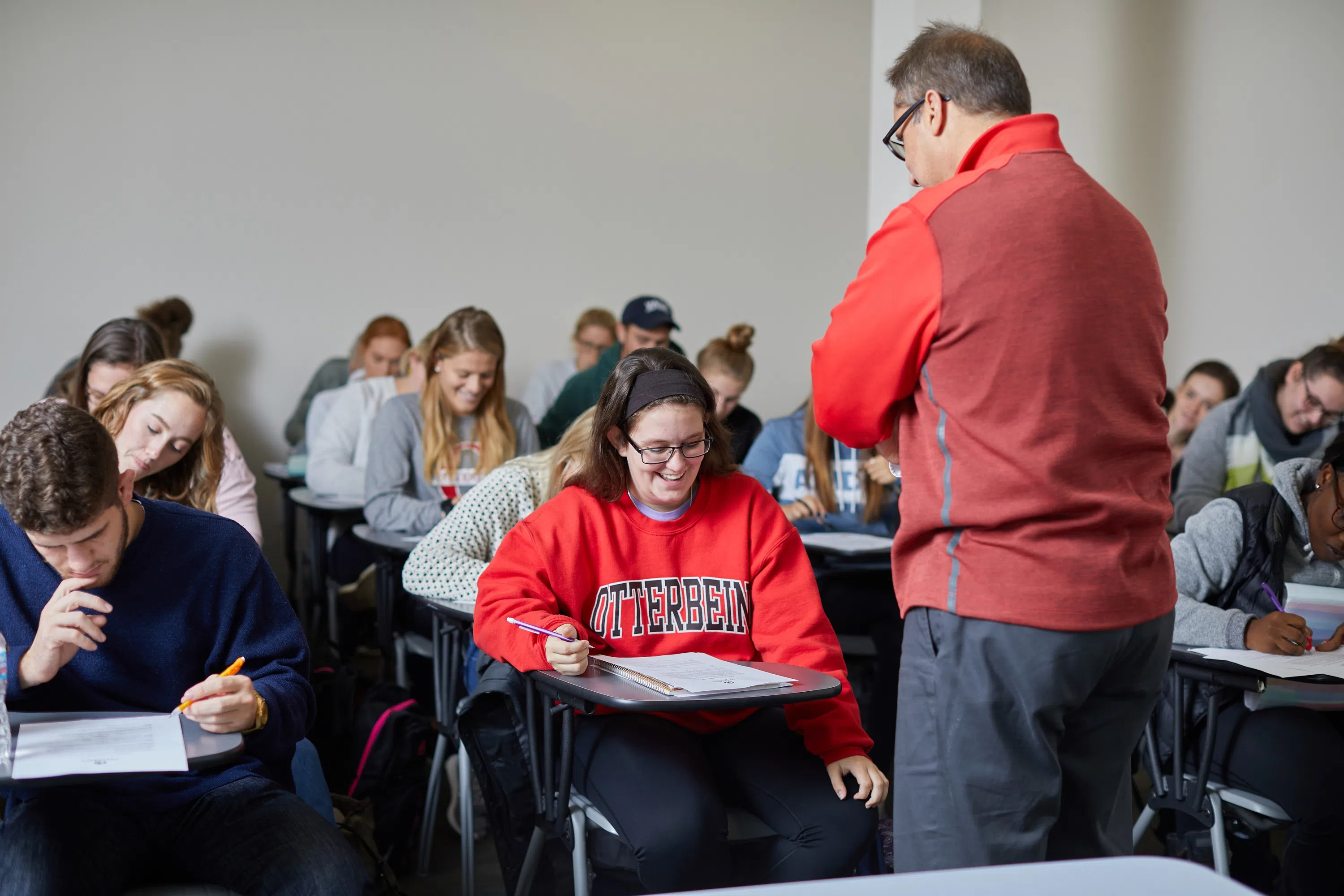 A full classroom working with an instructor at the front assisting students.