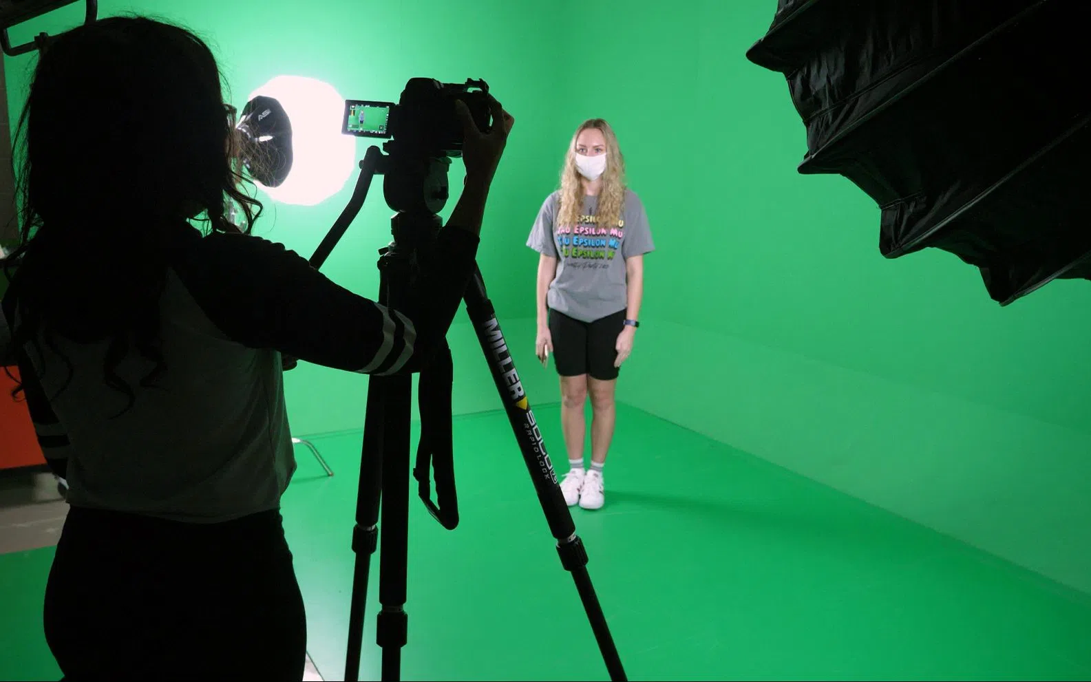 A person is being recorded in a bright green screen room