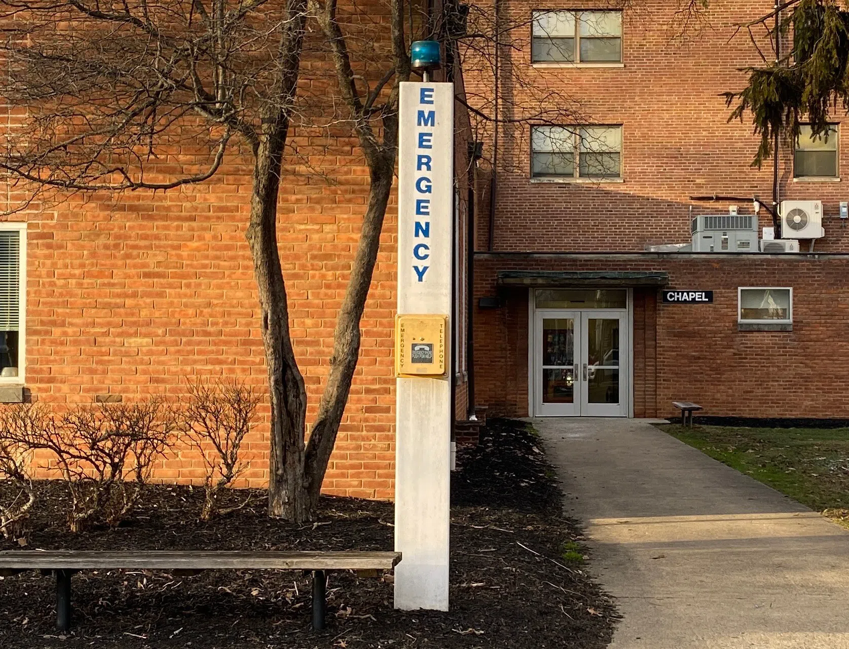 A white pole with a blue light at the top. It reads: "Emergency" in all capital letters.