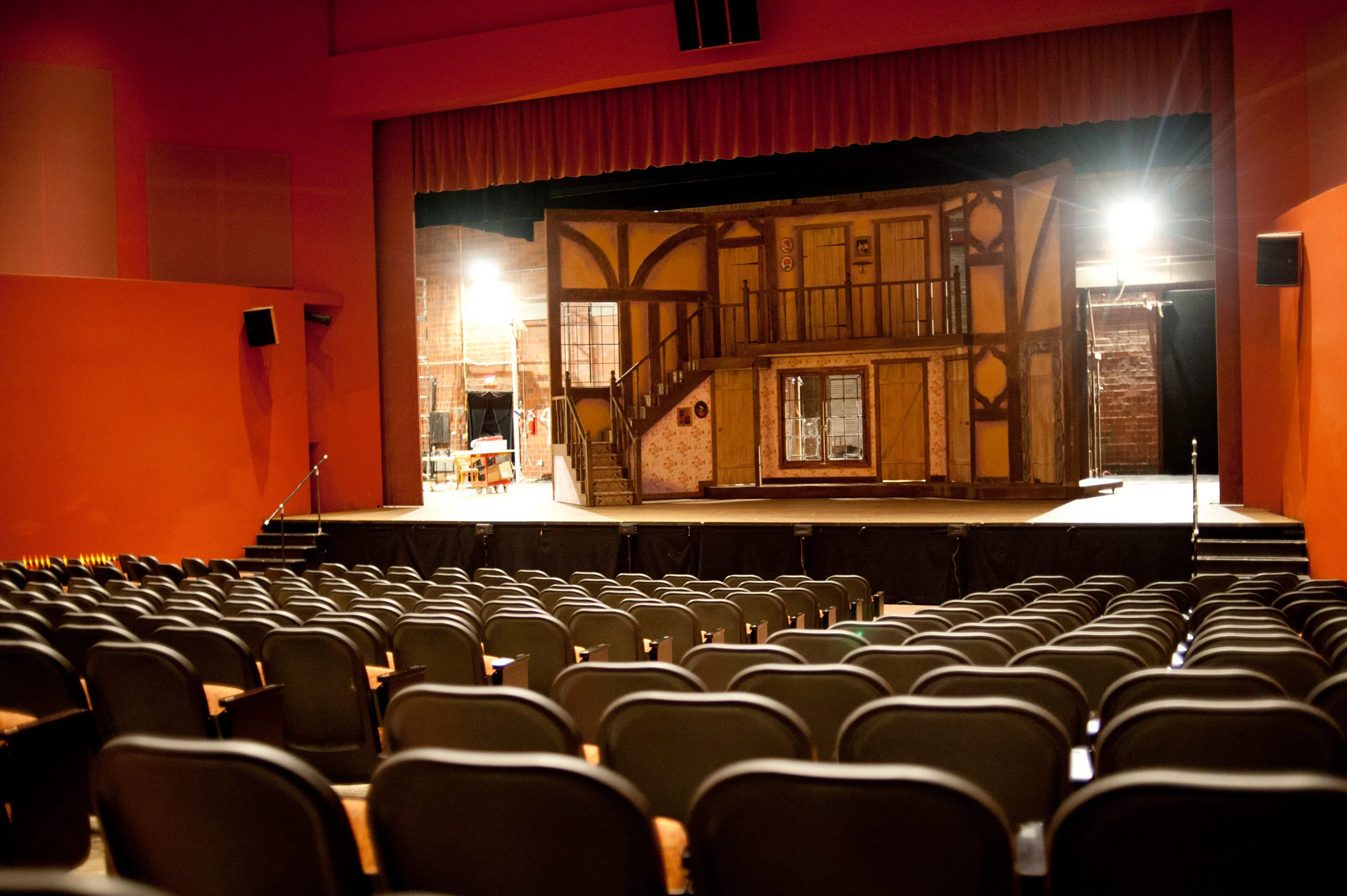 A brightly lit theater area with a wooden set on stage.