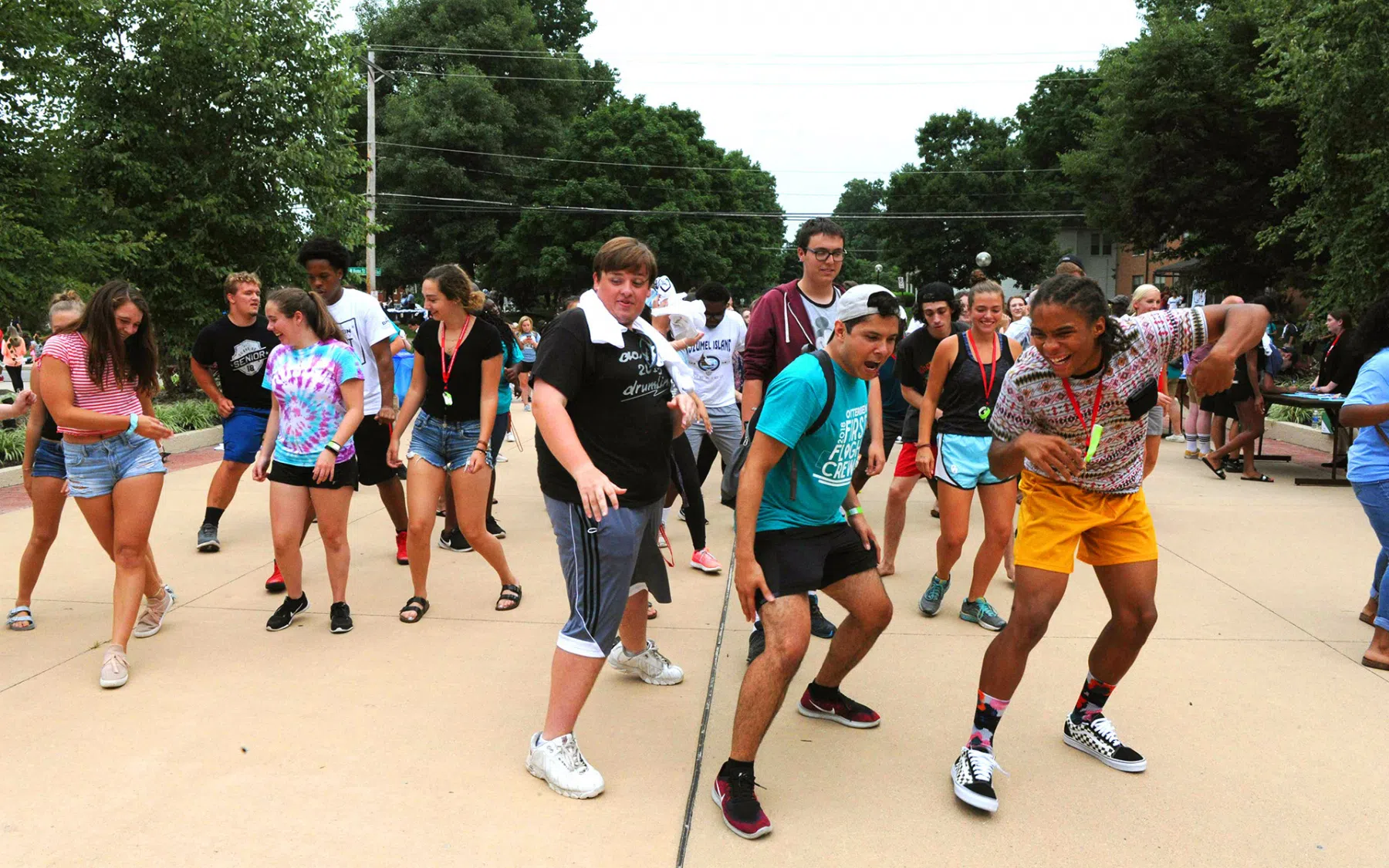 A group of students dance in an open space between Barlow Hall and the Campus Center during new student orientation.