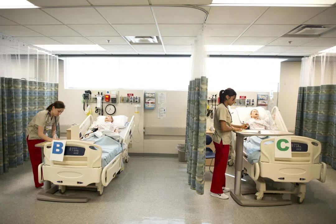 Two nursing simulation lab stations with students standing over each