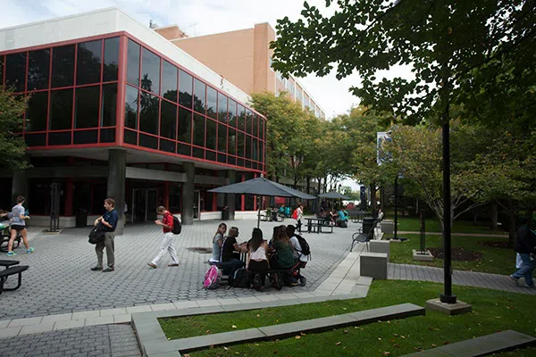 This is the front of Evans Hall featuring large windows and students sitting and walking outside.