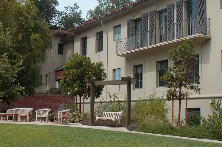 Tan building with chairs and bench on swing in forefront