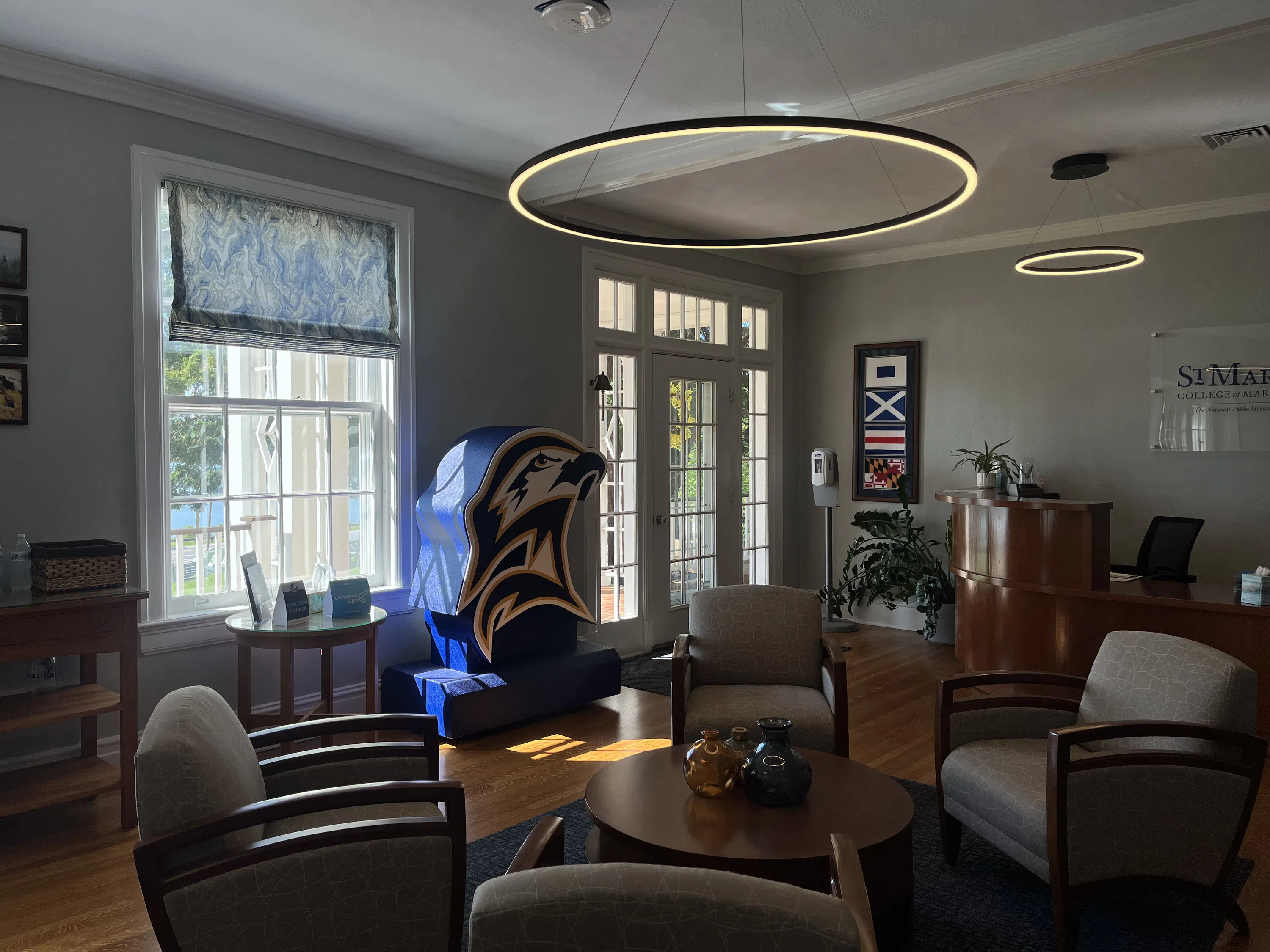 The admission welcome center visitor entrance to the Lobby, The front desk, front door, seating for four around a coffee table, a 3D large-scale portrayal the College's seahawk head logo.