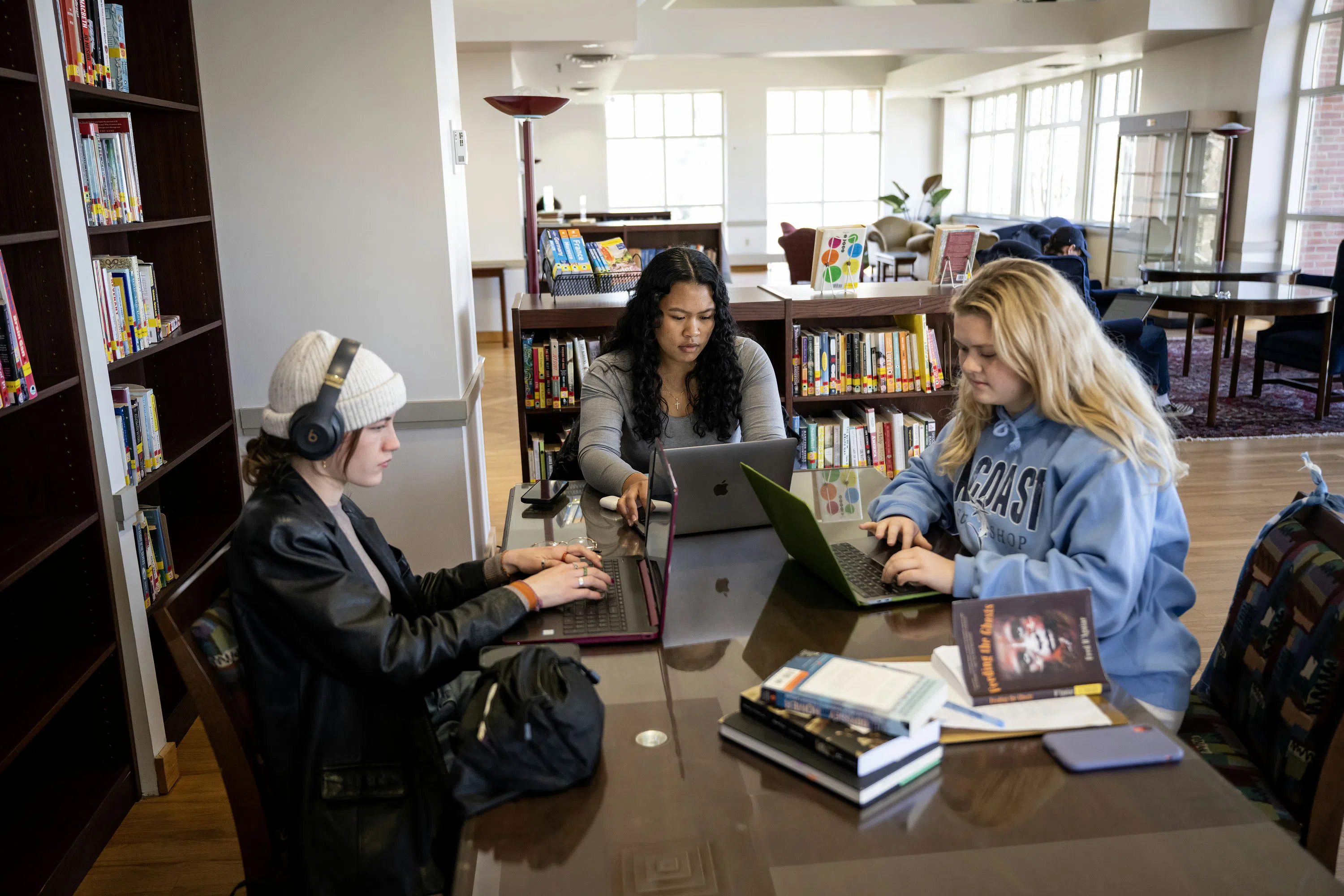 Three students seated at a table on the third floor of the library.