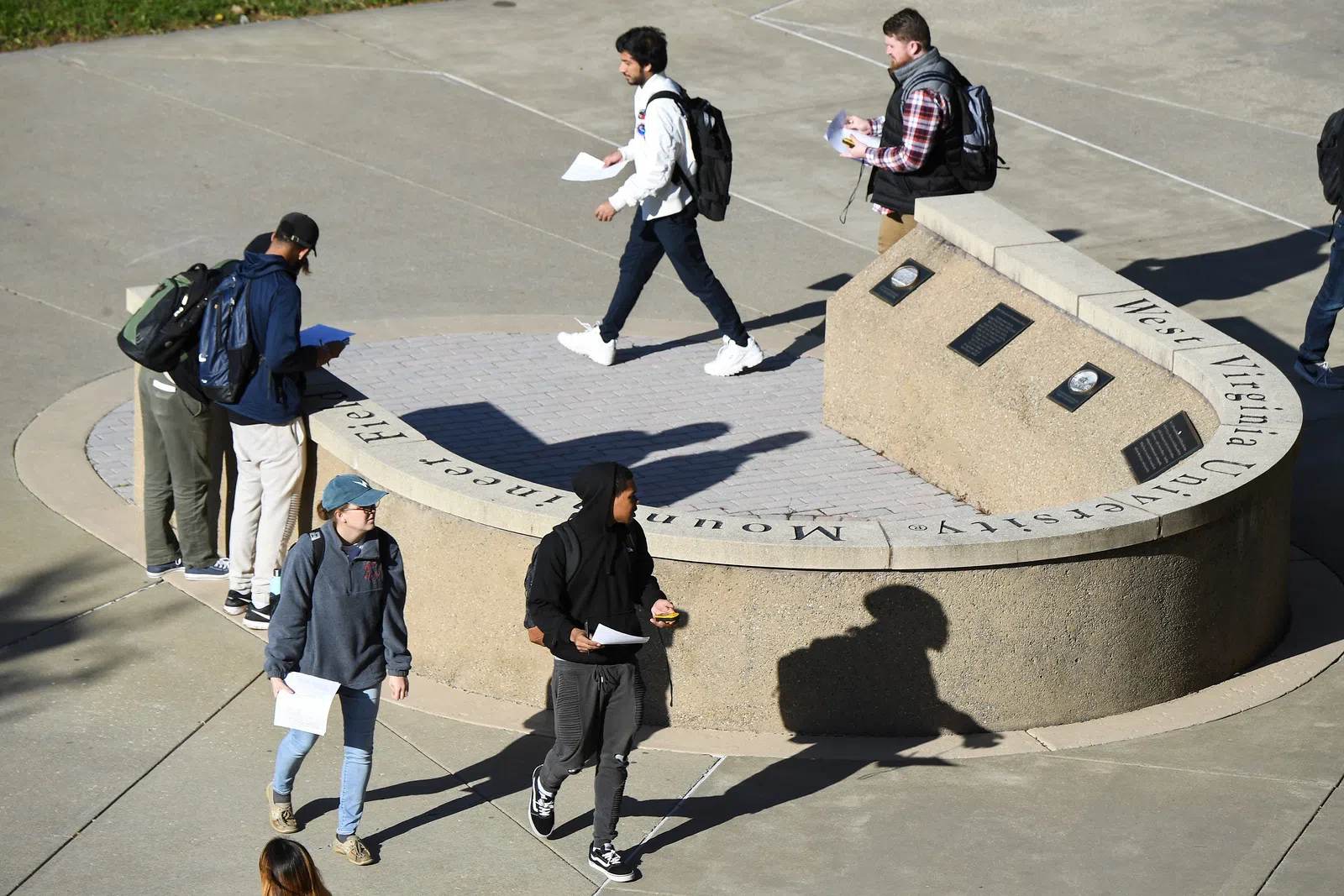 Image shows students walking around the U-shaped plaque indicating the former location of Old Mountaineer Field. 