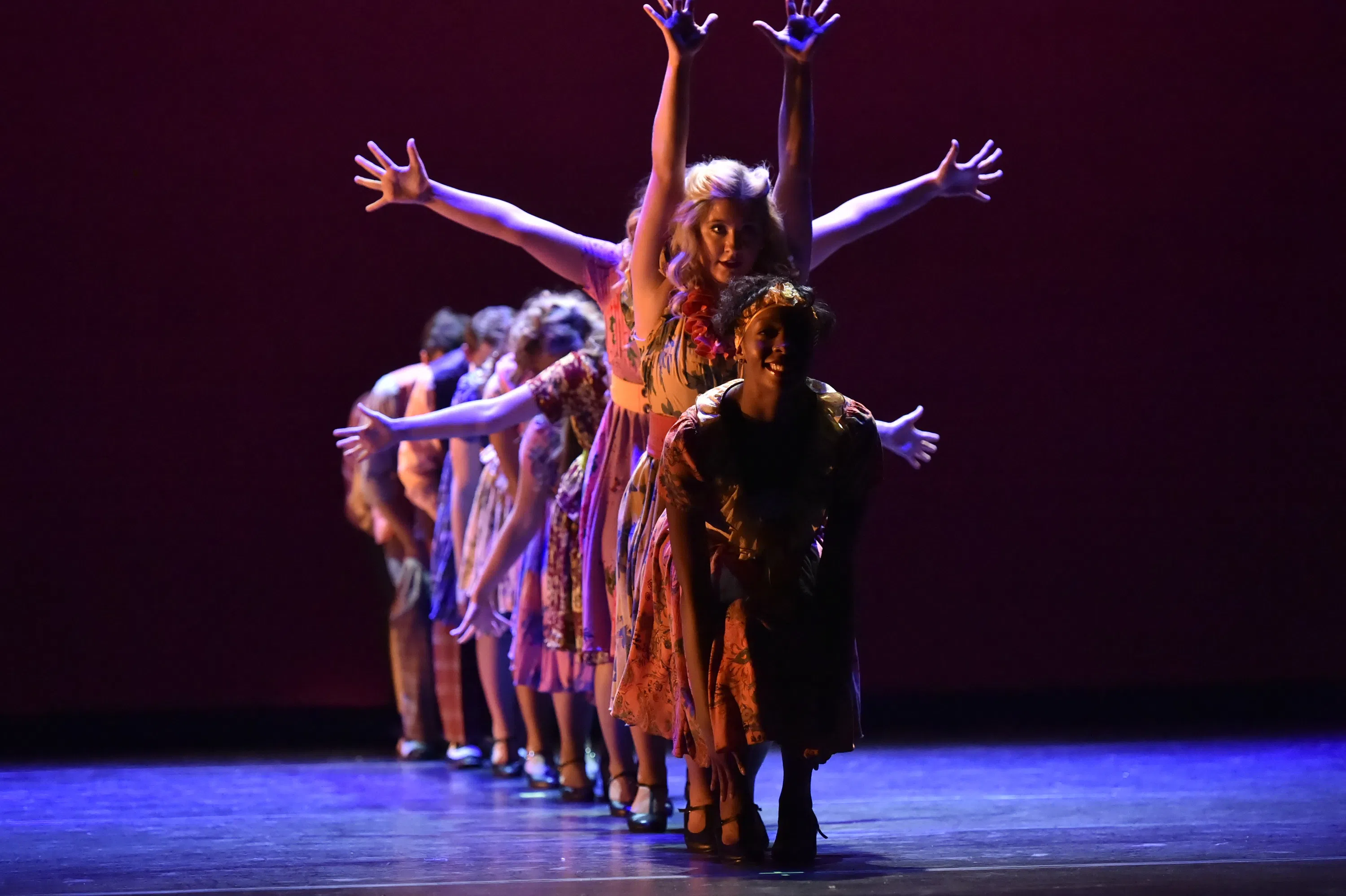 Dancers extend their arms on stage 