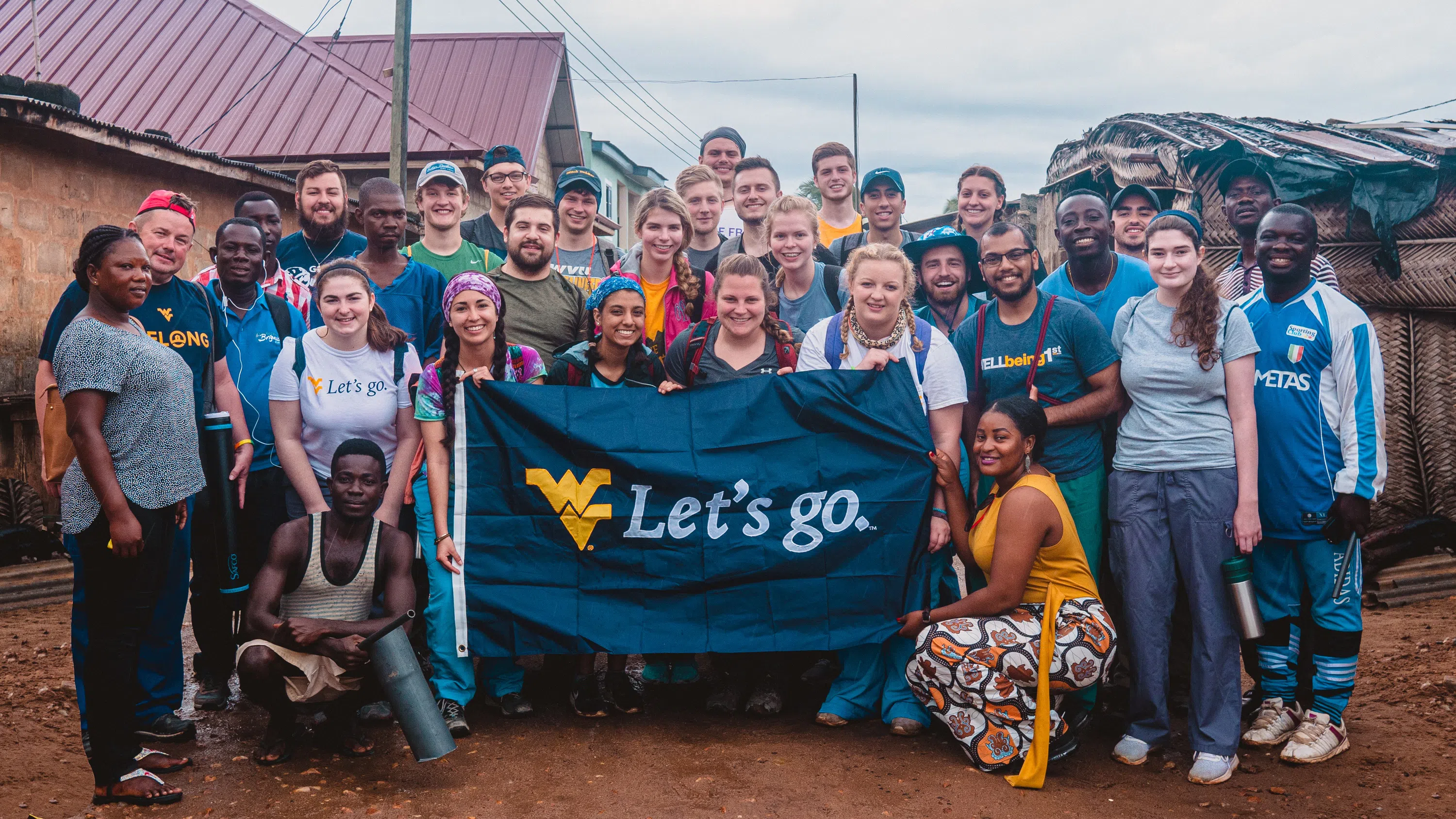 A group fo WVU students pose for a photo on their Study Abroad Program holding a WVU Flag. 