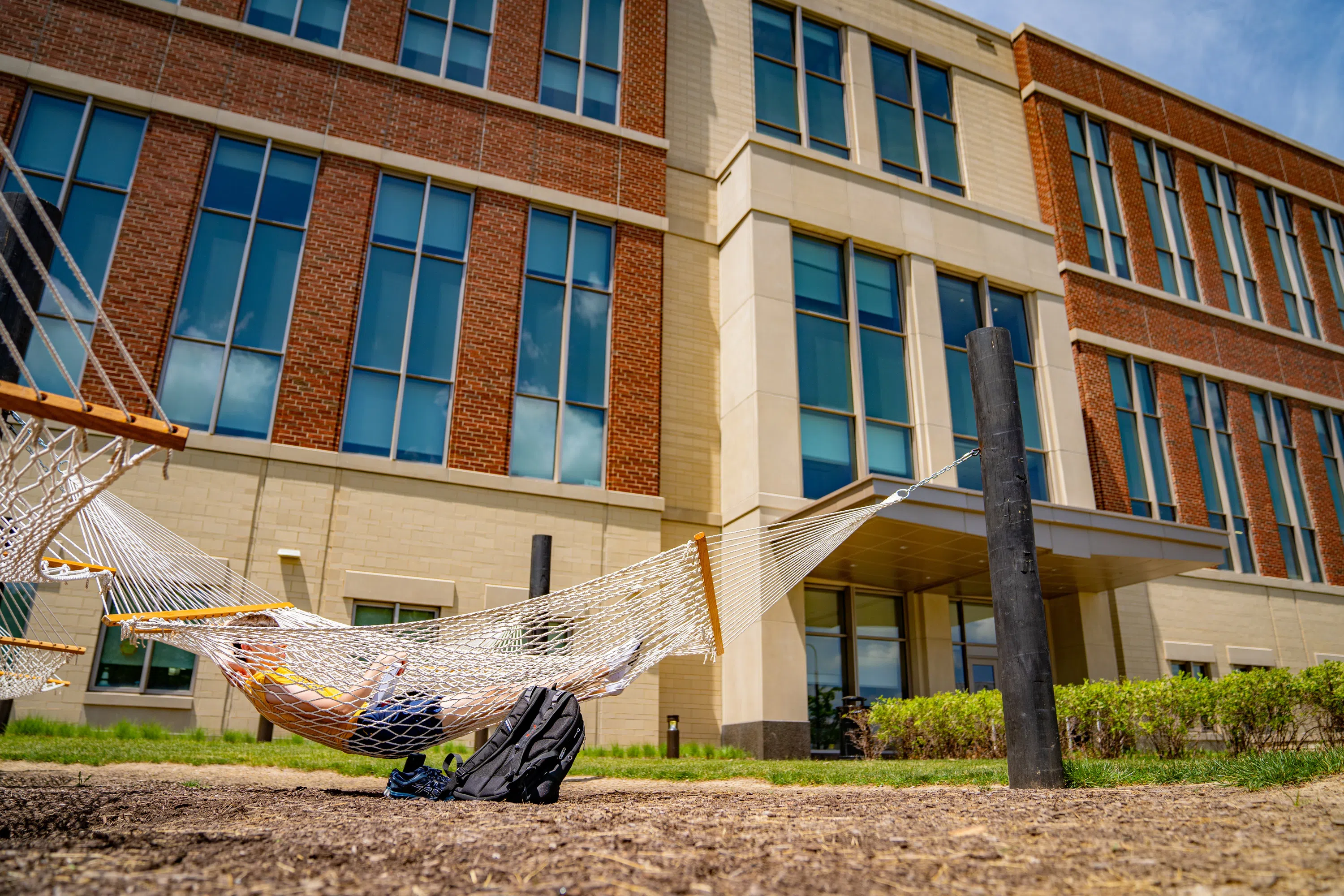 A Student lays in a hammock on the back side of the Agricultural Sciences Building 