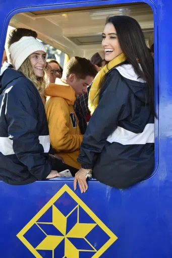 Two members of the dance team sit on the edge of a PRT car window.