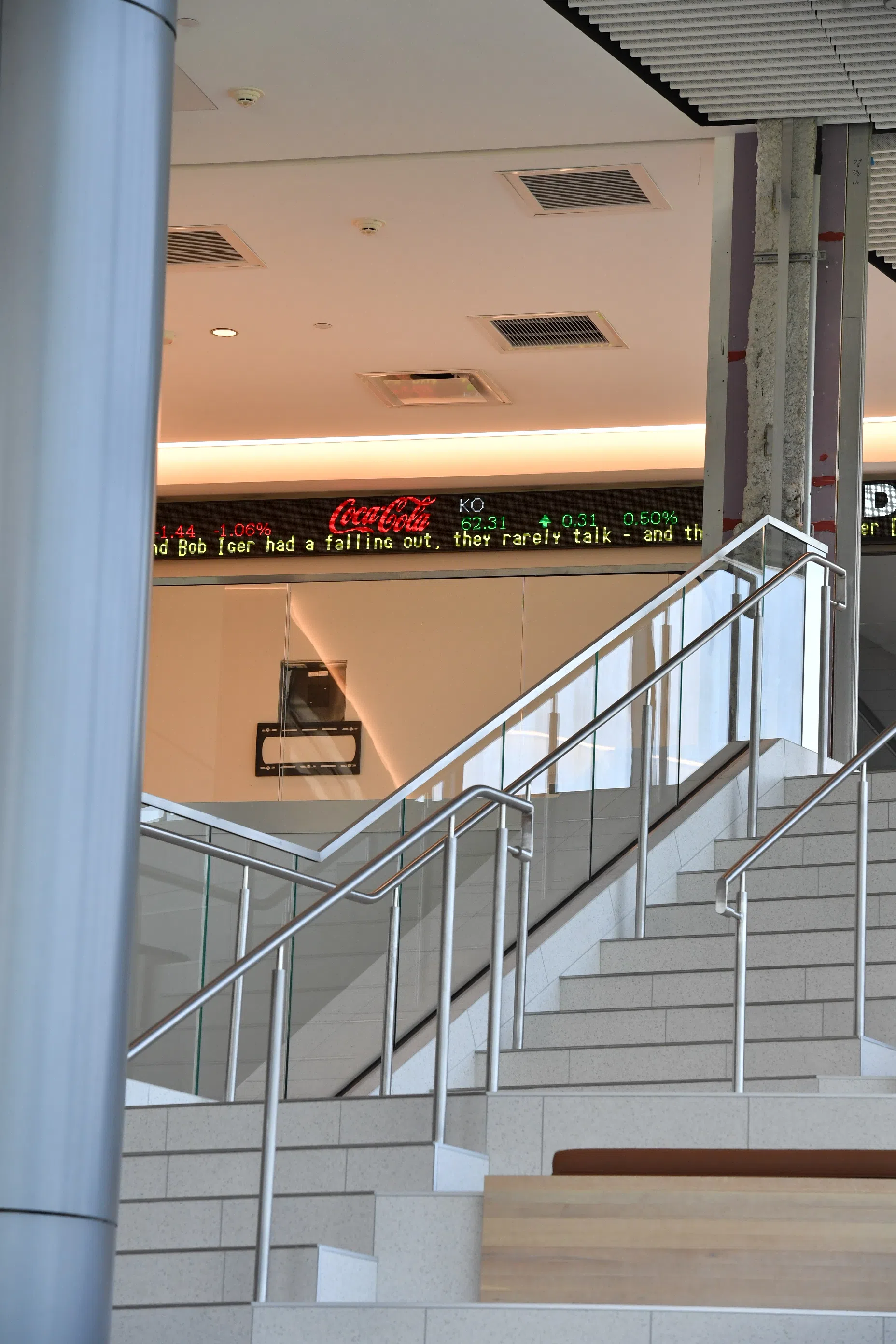 Image shows the top of the Reynolds Hall grand staircase and features a digital stock exchange banner. 