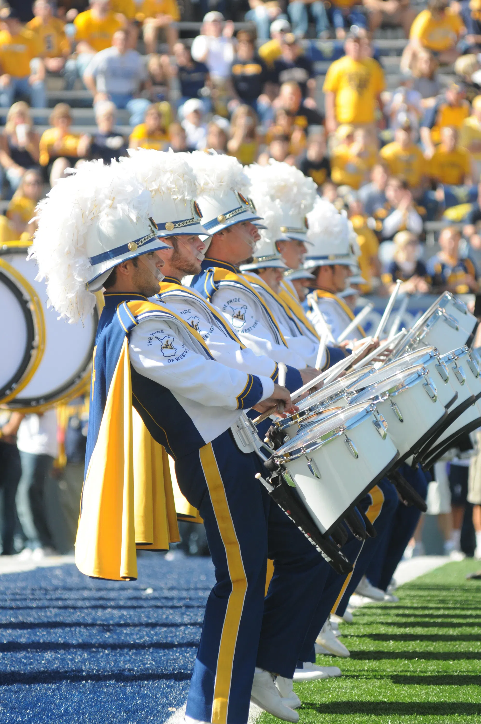 The drum line stands on the edge of the end zone in full uniform.