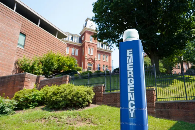 A photo of a blue pole with the word "Emergency" written on it and a light on the top. 