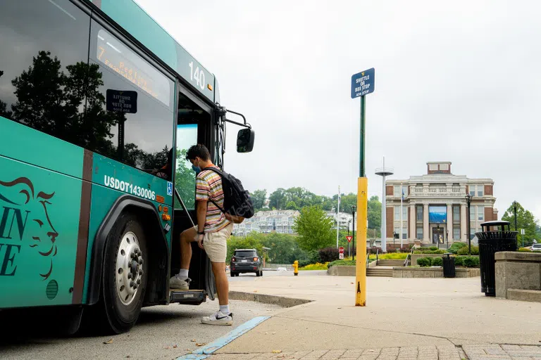 Student boarding mountain line transit authority bus in front of the downtown student union, the Mountainlair. 