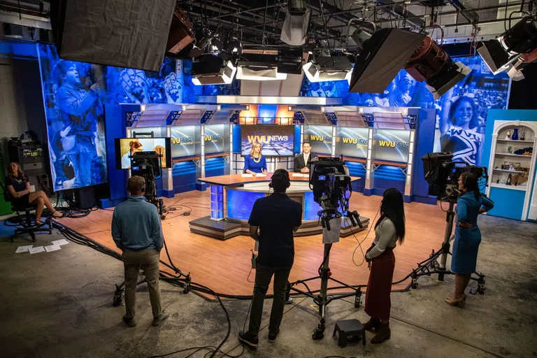 An action shot of WVU students filming a news broadcast. 