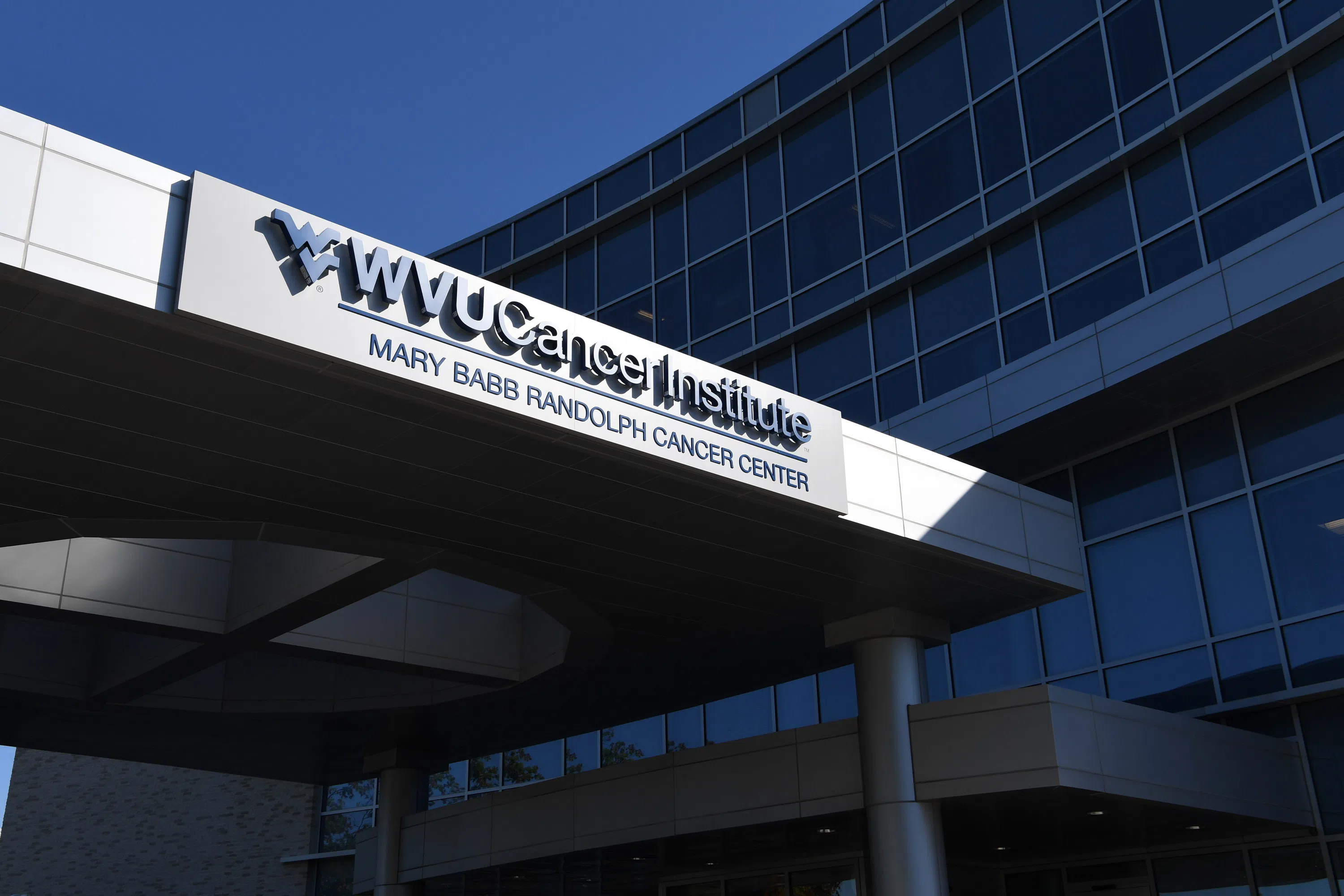 A sign on a building with glass windows reads "WVU Cancer Institute Mary Babb Randolph Cancer Center."