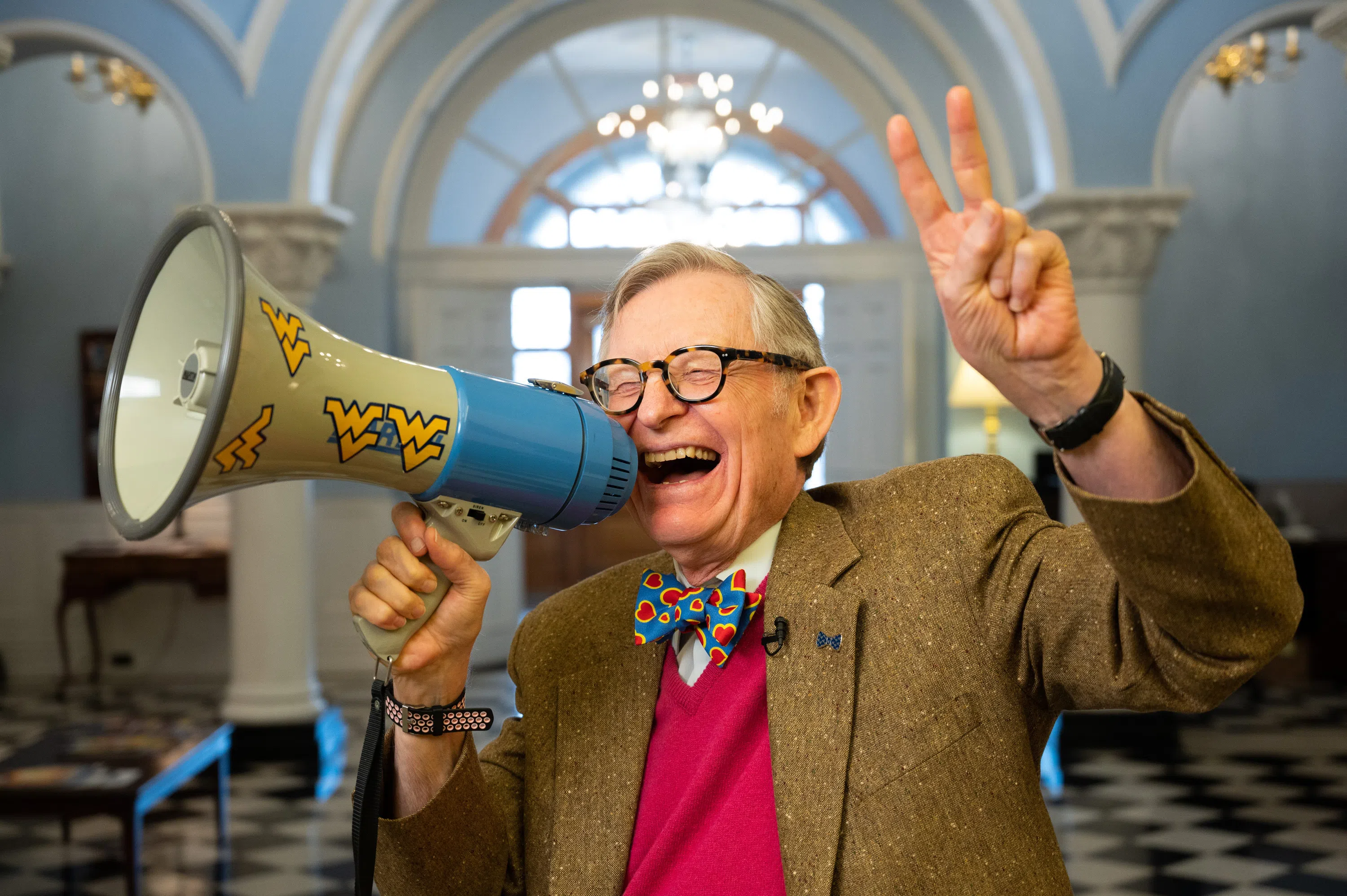 Dr. E. Gordon Gee poses with a megaphone and holds up a peace sign.
