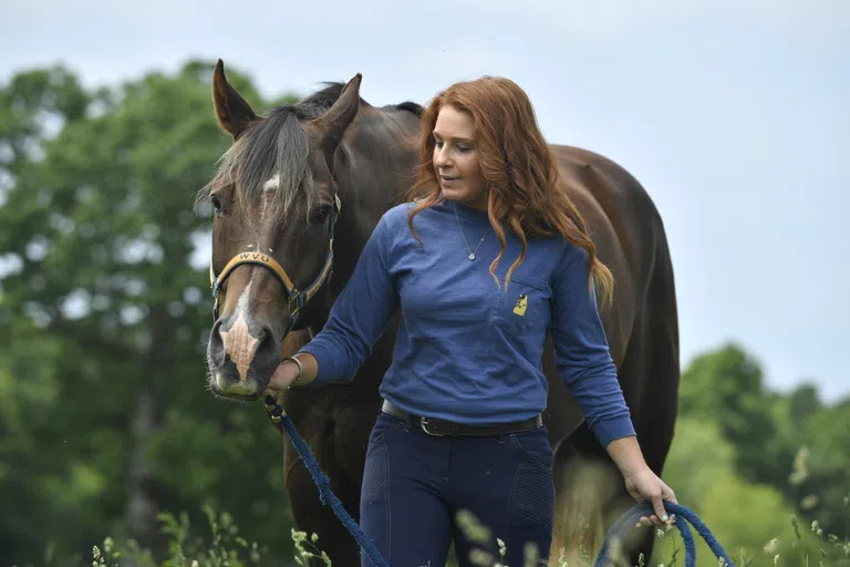 A student leads a horse through a field 