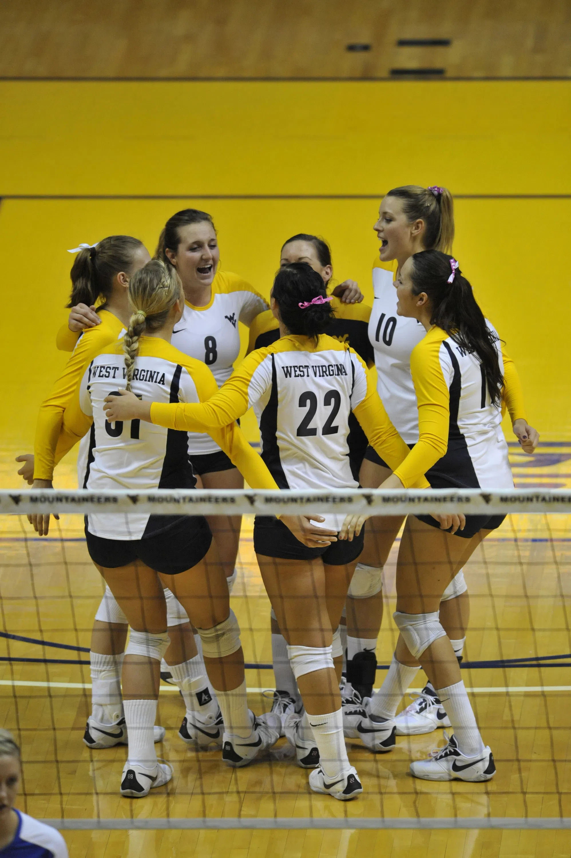 A group of volleyball players huddle on the court.