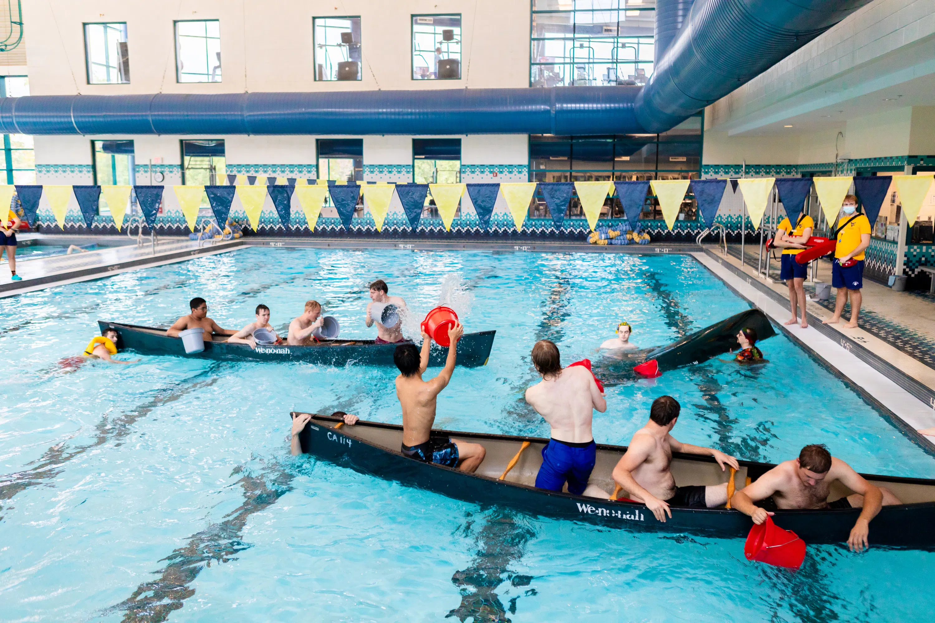 Students in two canoes within the olympic style-lap swimming pool playing canoe battleship. 