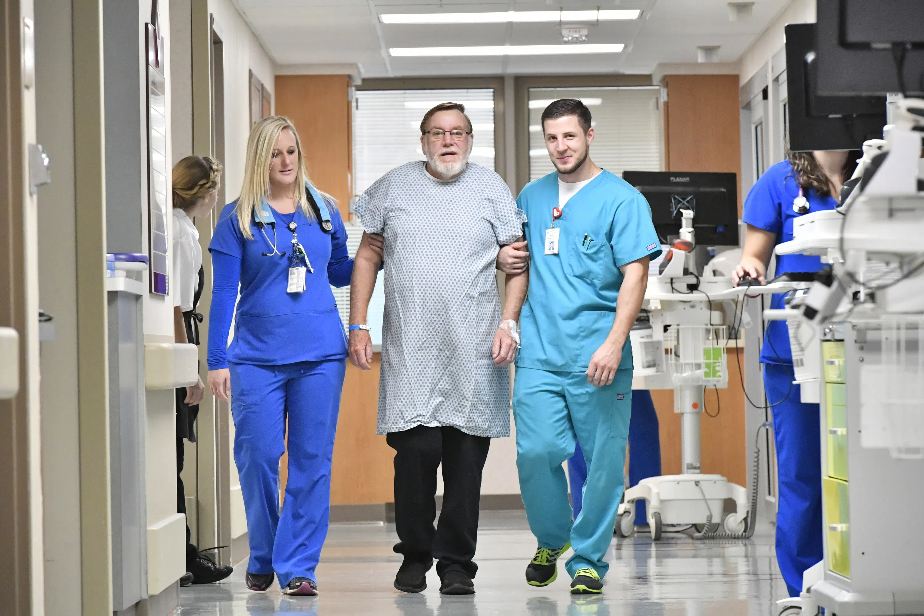A patient is walked down the hall by two nurses.