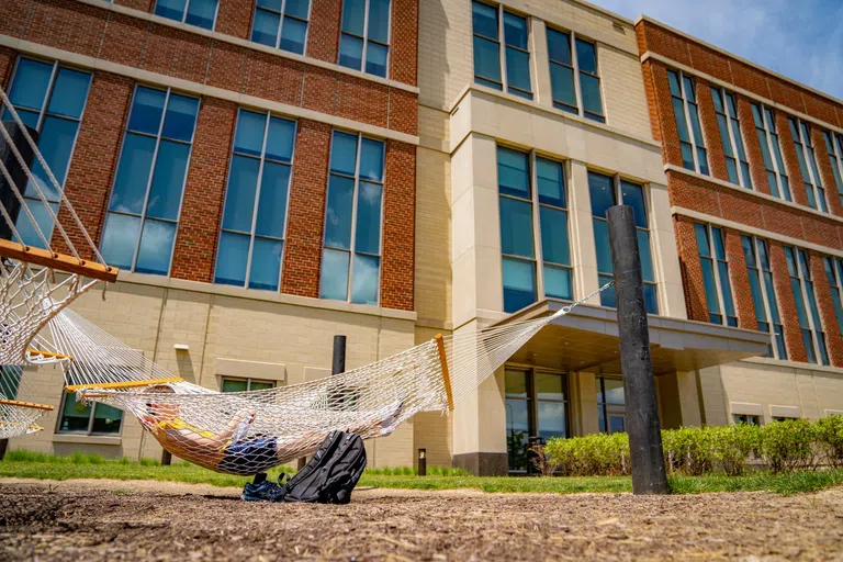 A Student lays in a hammock on the back side of the Agricultural Sciences Building 