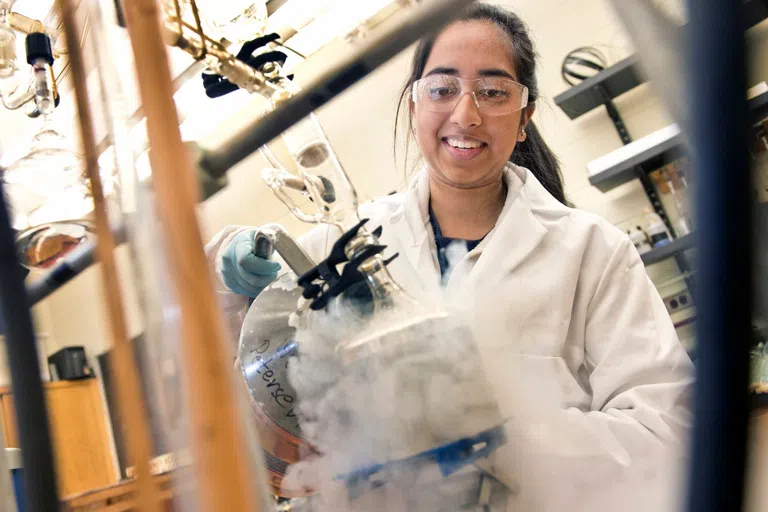 A student pours a liquid in a canister that produces steam 