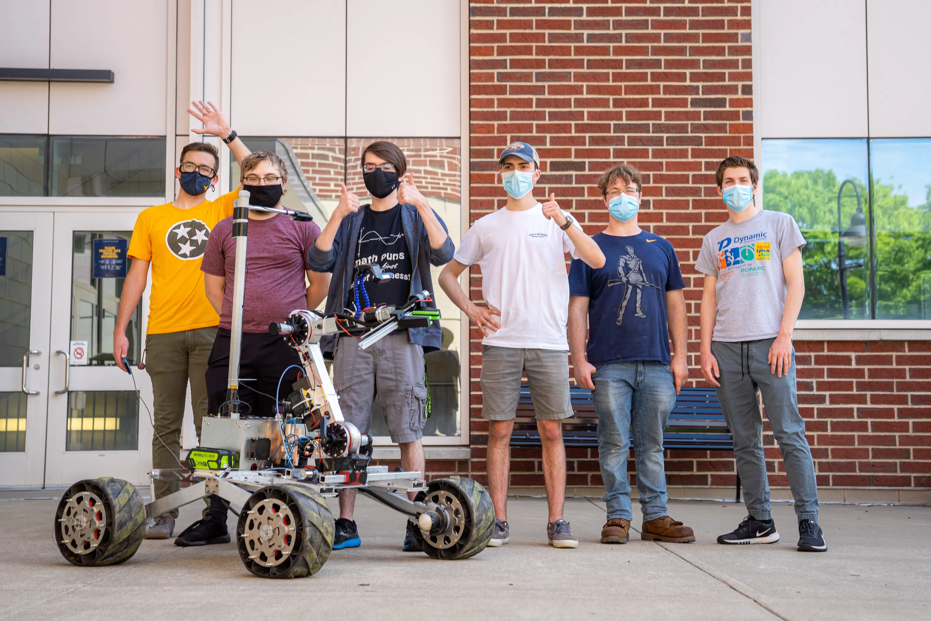 A group of students stand with a Mars Rover Robot 