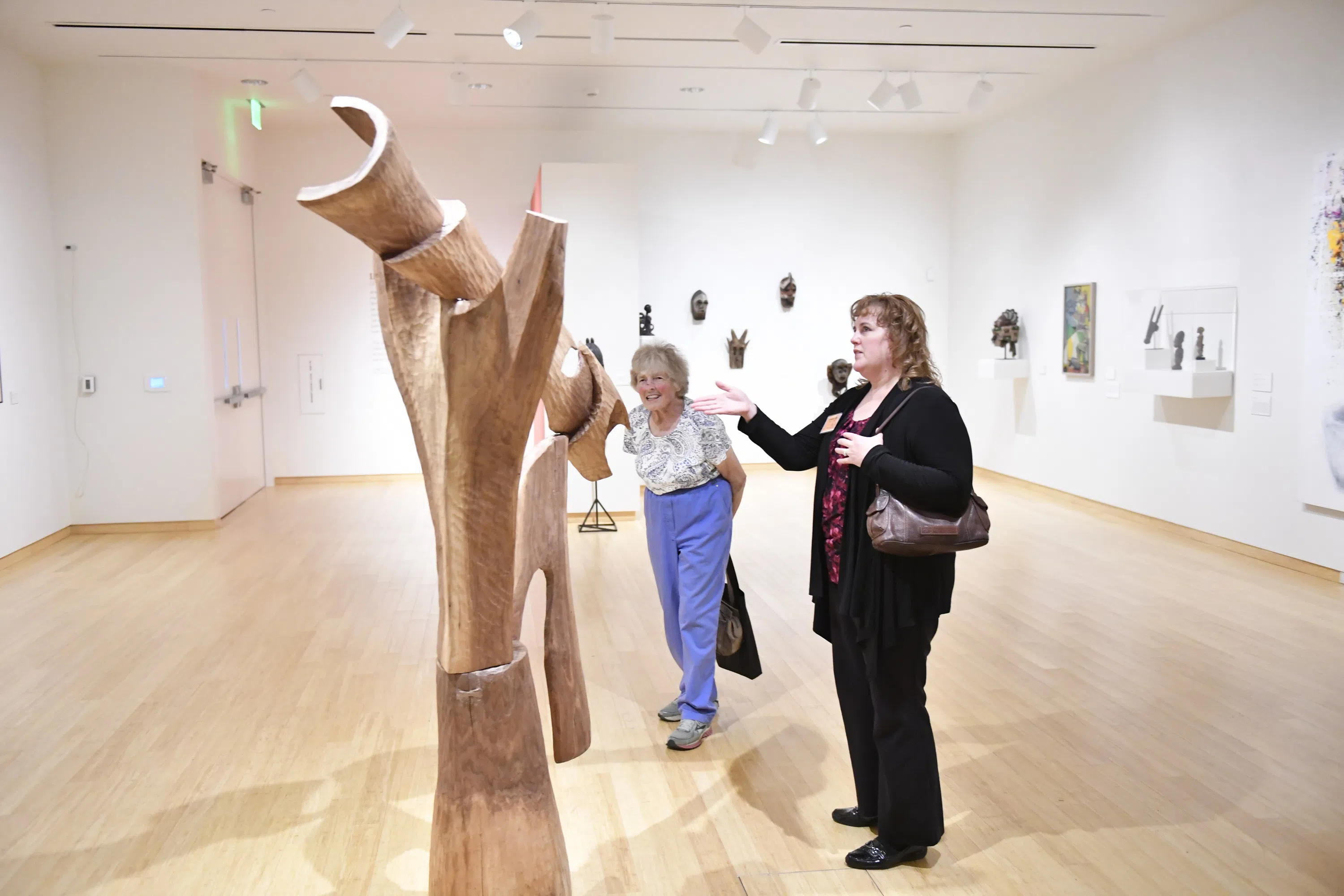 Members of the community point and talk about a sculpture inside the Art Museum. 